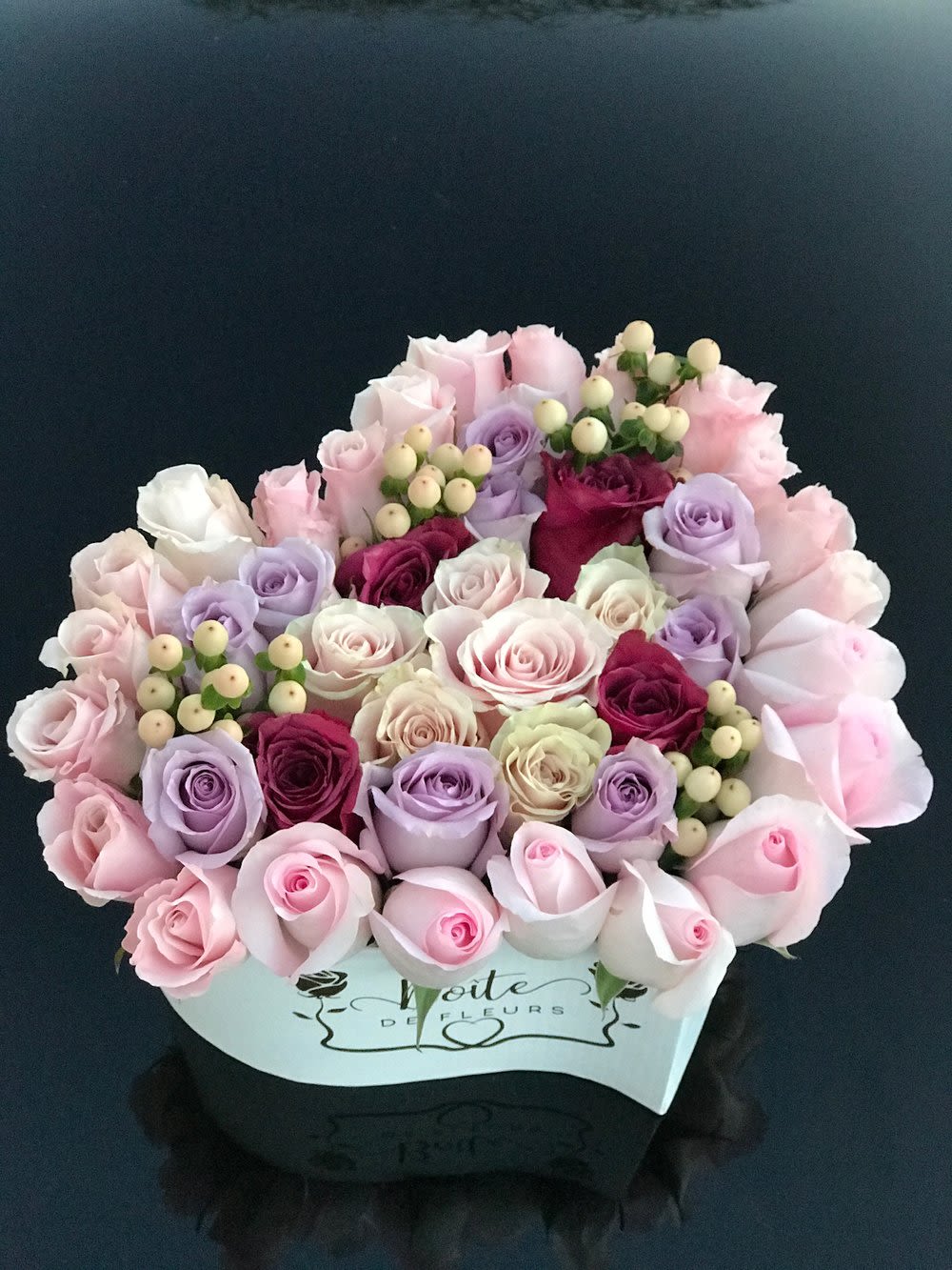 Bouquet of pastel roses and berry sprigs in a white box