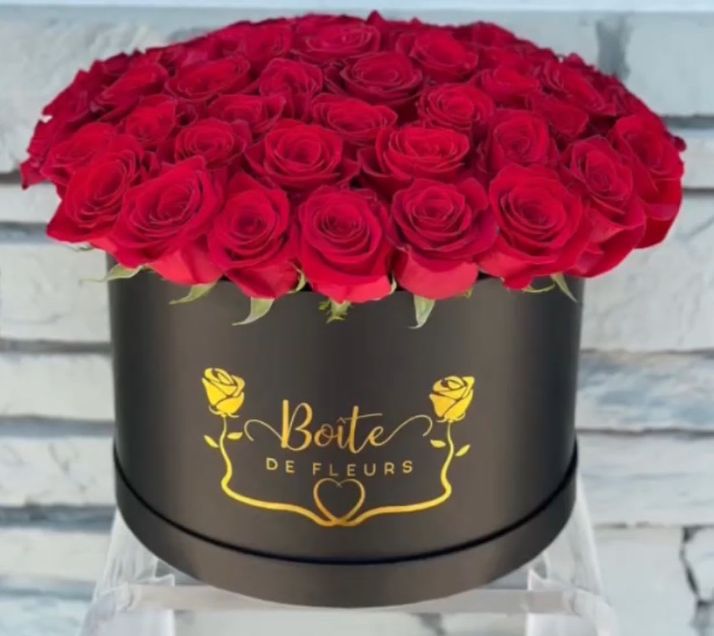 Red roses arranged in a black round box with gold lettering