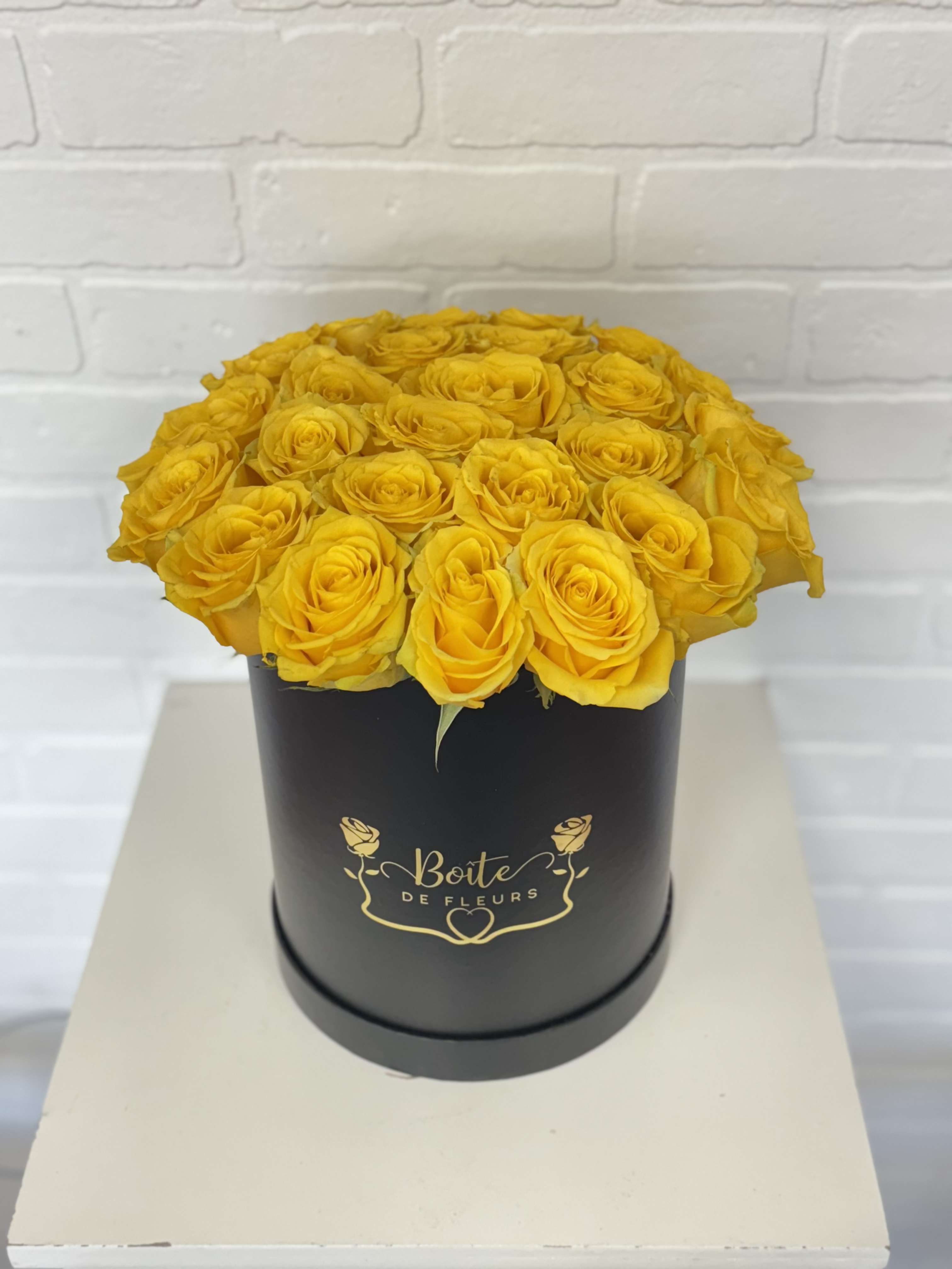 Yellow roses arranged in a black round box