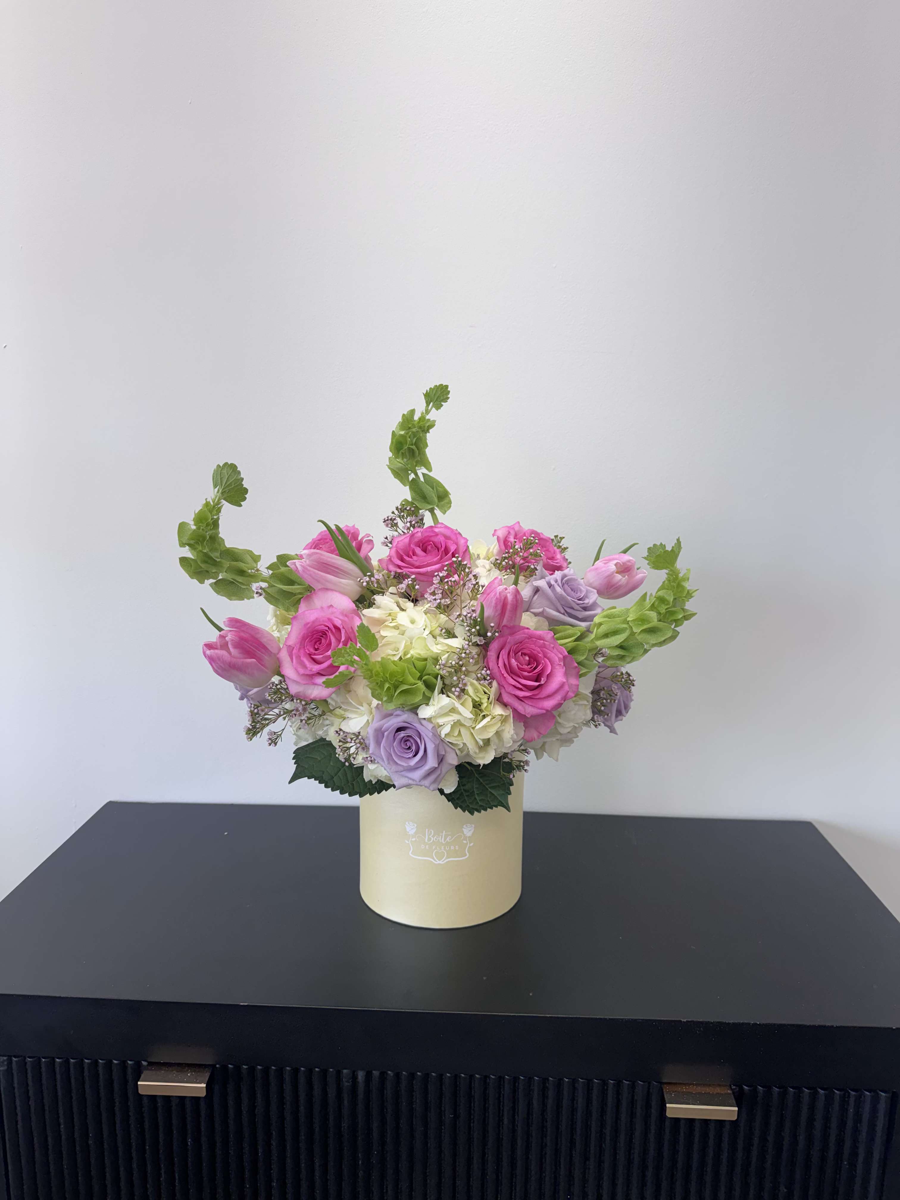Pink and lavender roses with tulips in a cream box