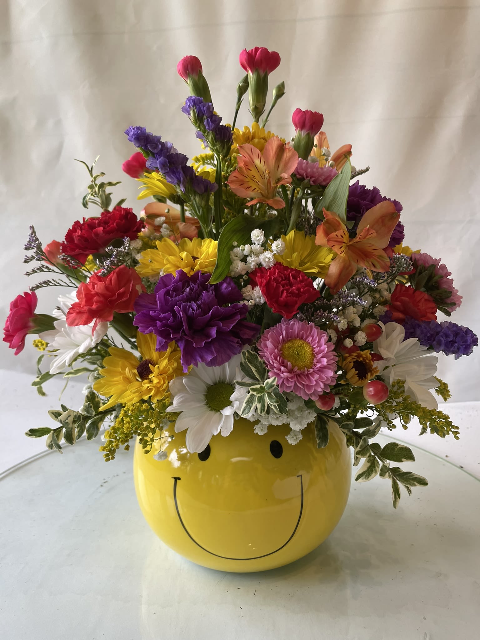 Colorful mixed flower arrangement in a yellow smiley-face vase