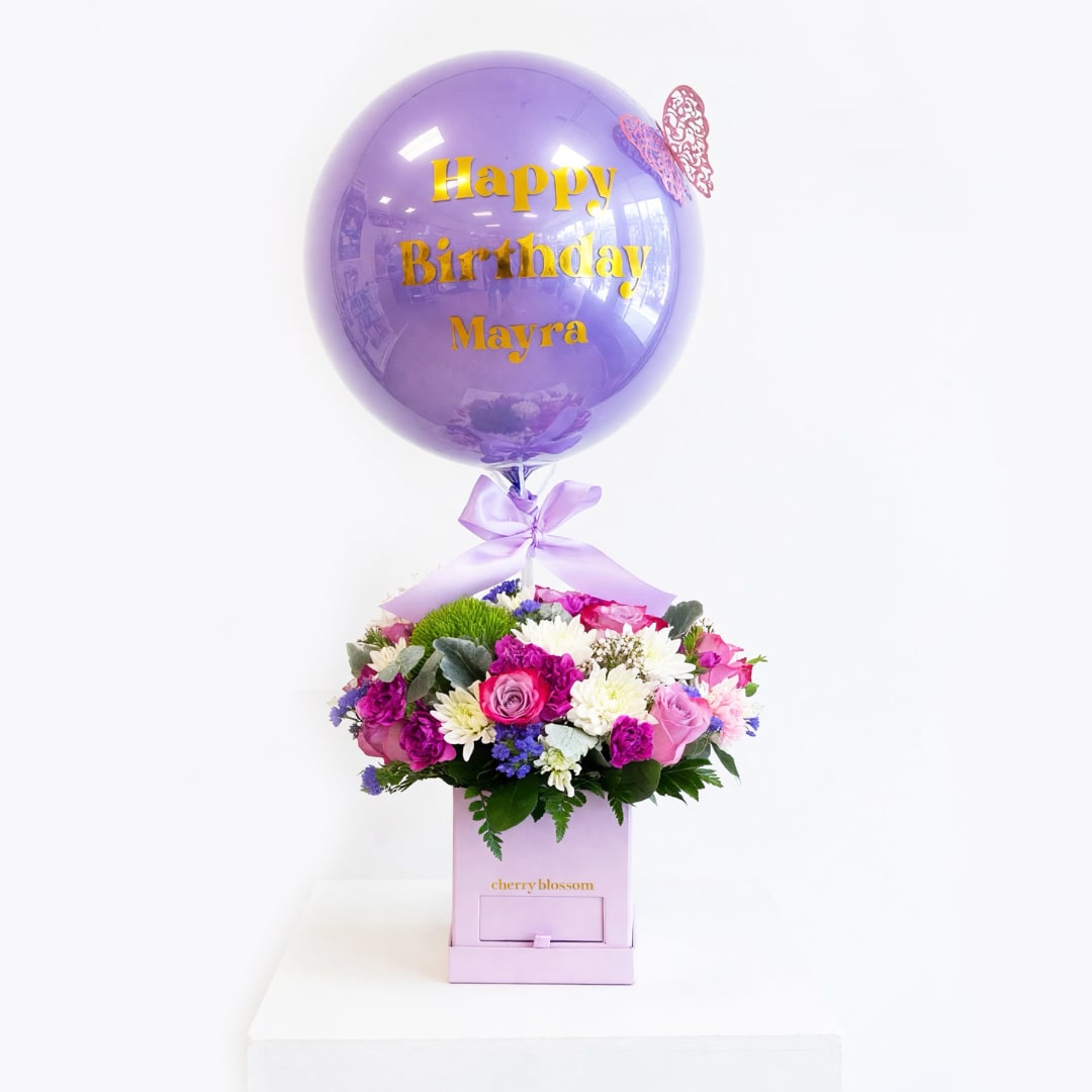 Birthday balloon above a mixed flower arrangement in a pink box