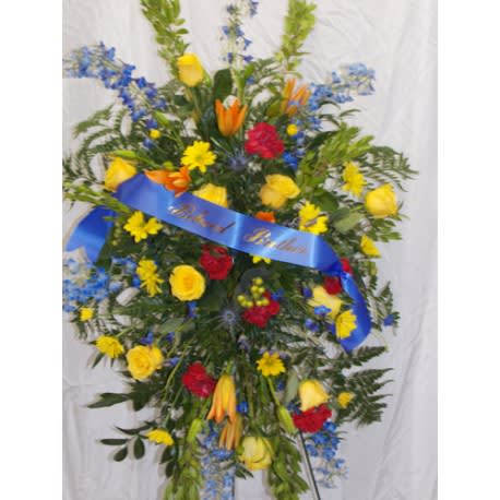 Standing floral spray with yellow, red, blue, and orange flowers on a blue ribbon