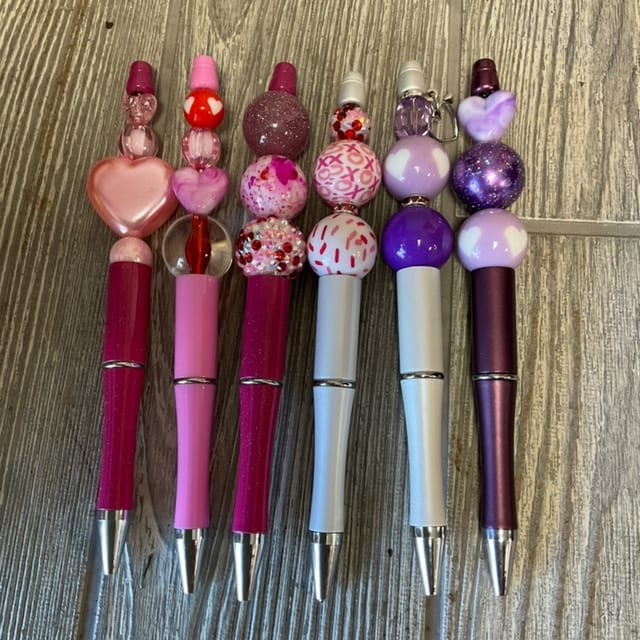 Decorative pens with beaded heart and glitter toppers in pink and purple.