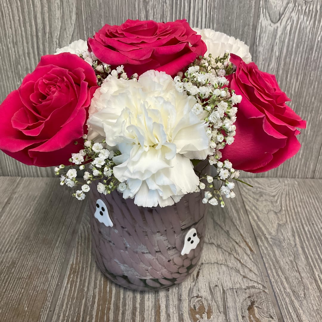 Pink roses and white carnations in a decorated vase with small ghost accents