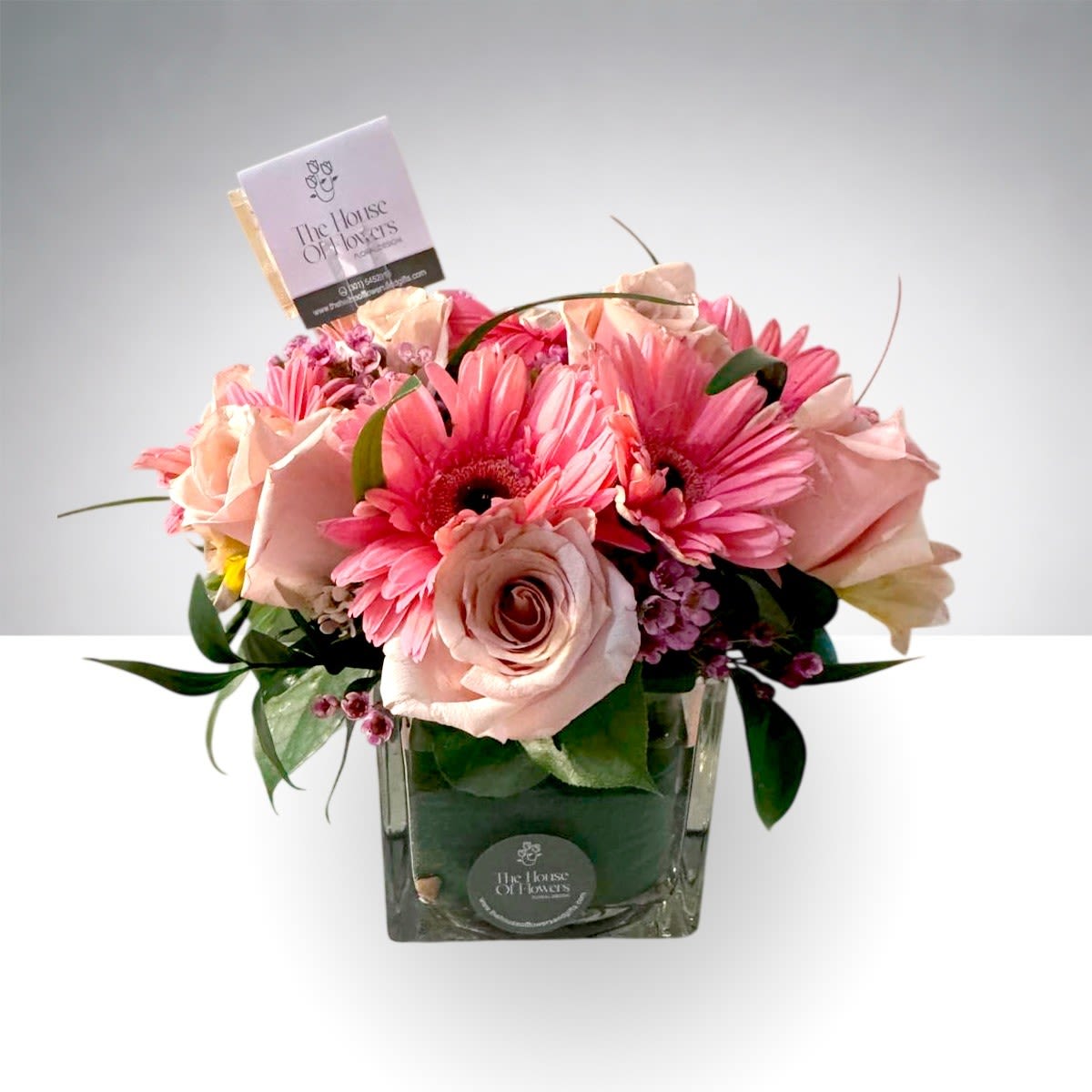 Blush Symphony by The House of Flowers - A romantic blend of premium roses and fresh seasonal blooms designed in a modern glass cube. Soft blush tones and elegant textures create a timeless look perfect for any occasion. Flower colors may vary based on availability and the client’s preferred color palette, ensuring each arrangement is uniquely crafted. Hand-designed with care and attention to detail by The House of Flowers MD.  APPROXIMATE DIMENSIONS OF THE BASE: 5" H, 5"L 