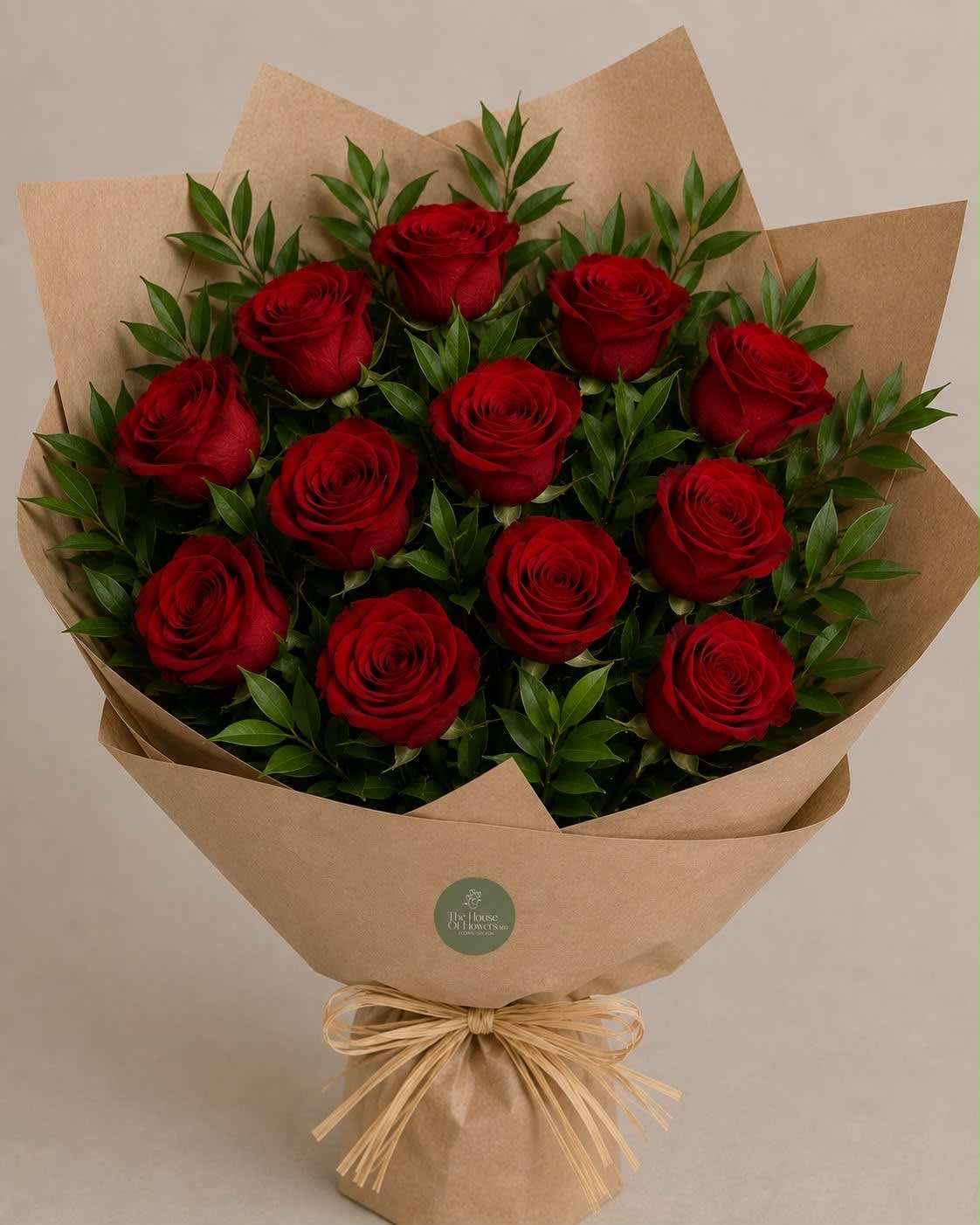Bouquet of red roses wrapped in brown paper with a raffia bow