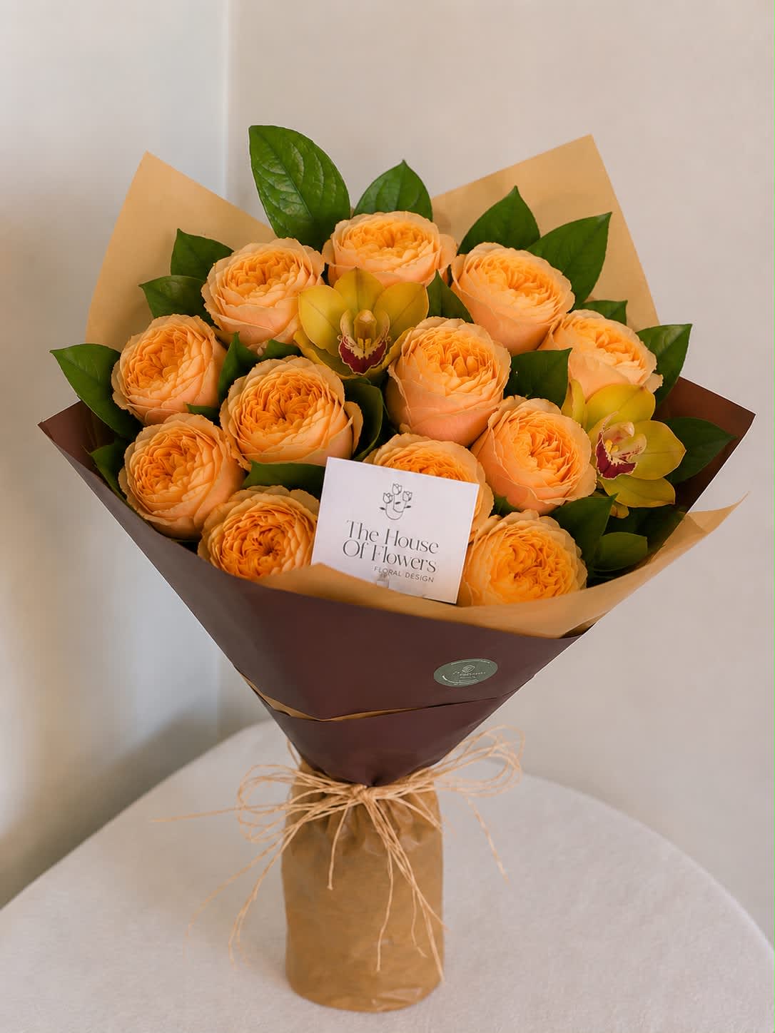 Bouquet of peach roses with yellow orchids wrapped in brown paper