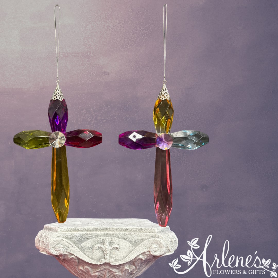 Two colorful crystal cross ornaments hang above a carved pedestal