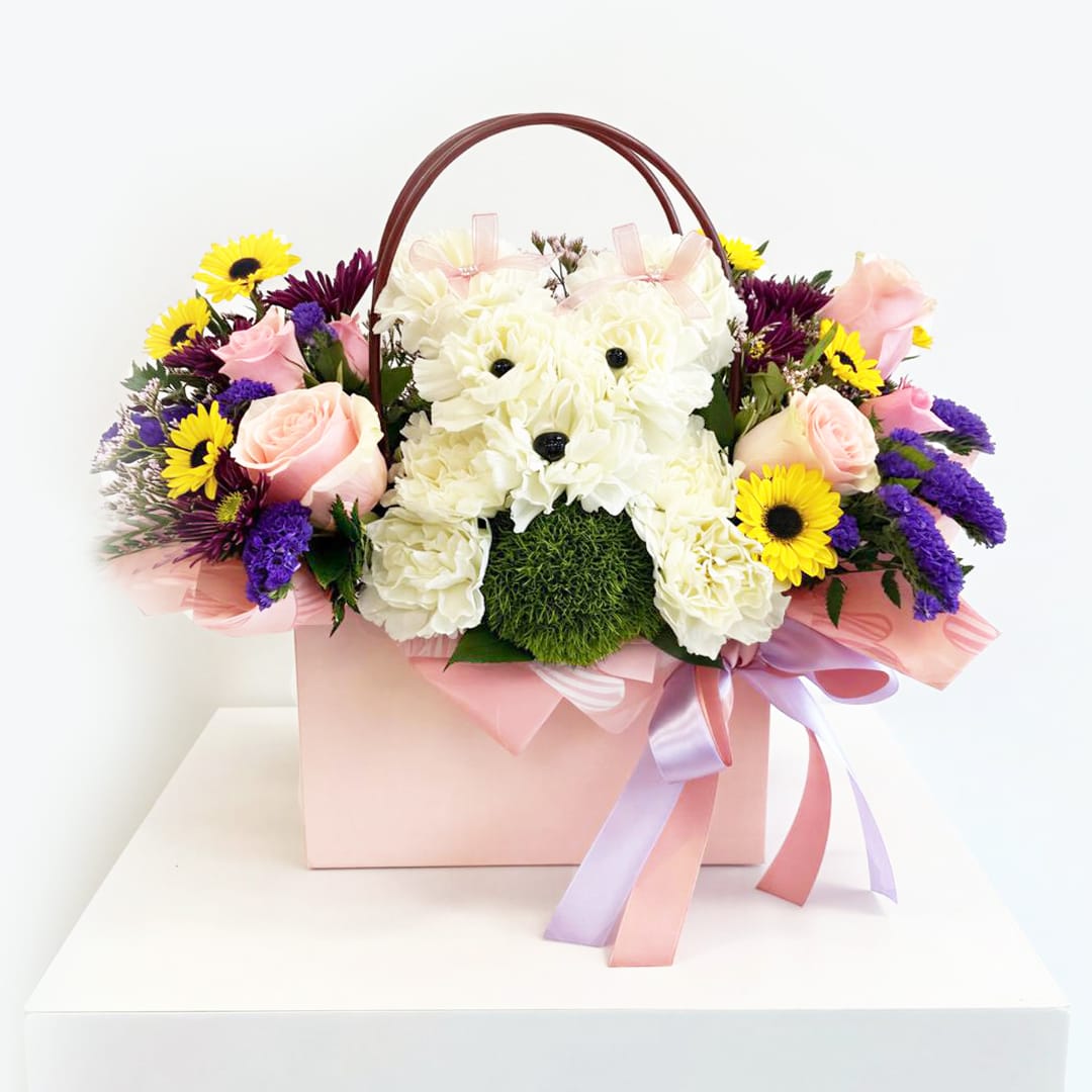 Pink and white floral arrangement in a gift box with a teddy bear face