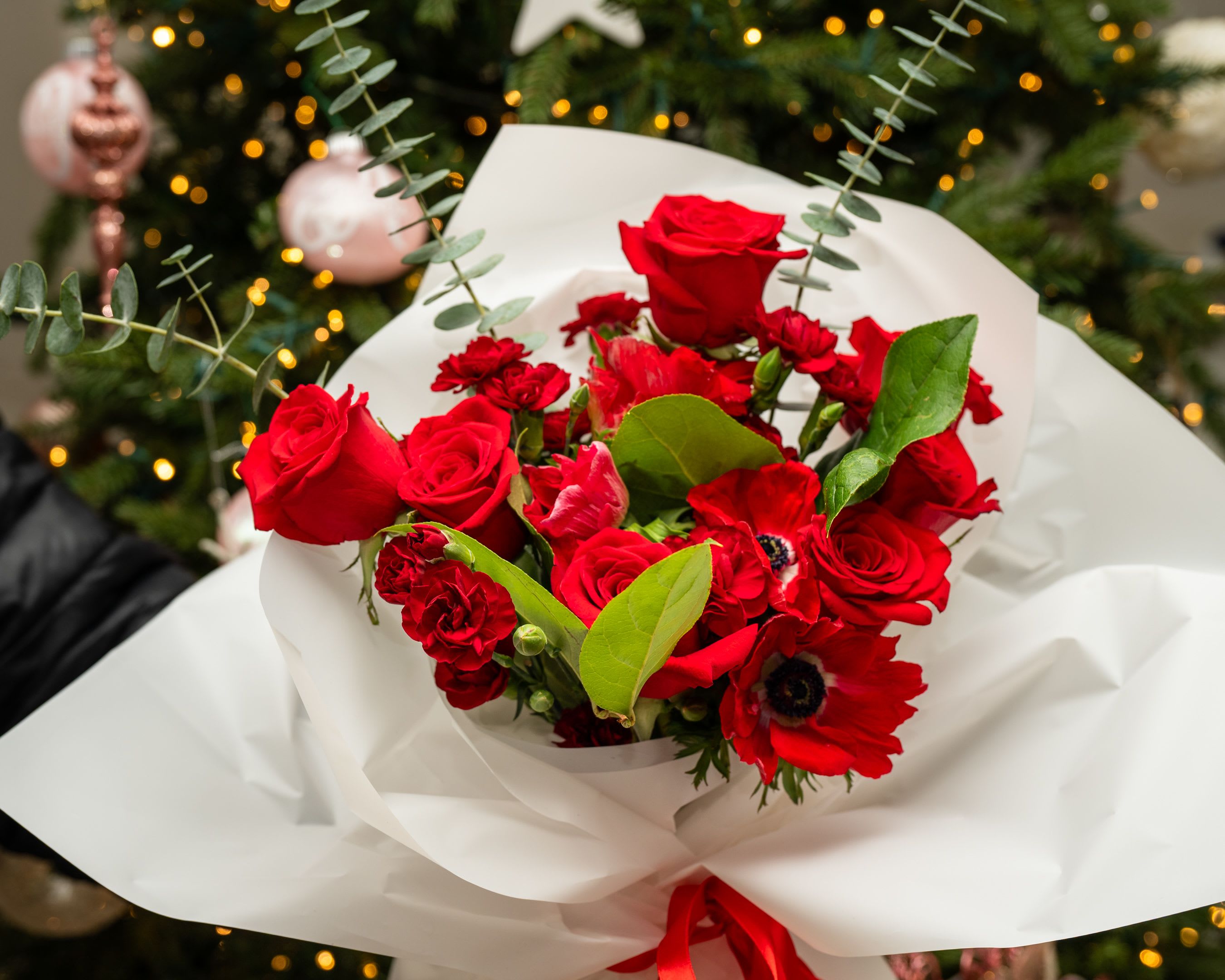 Bouquet of red roses and red anemones wrapped in white paper