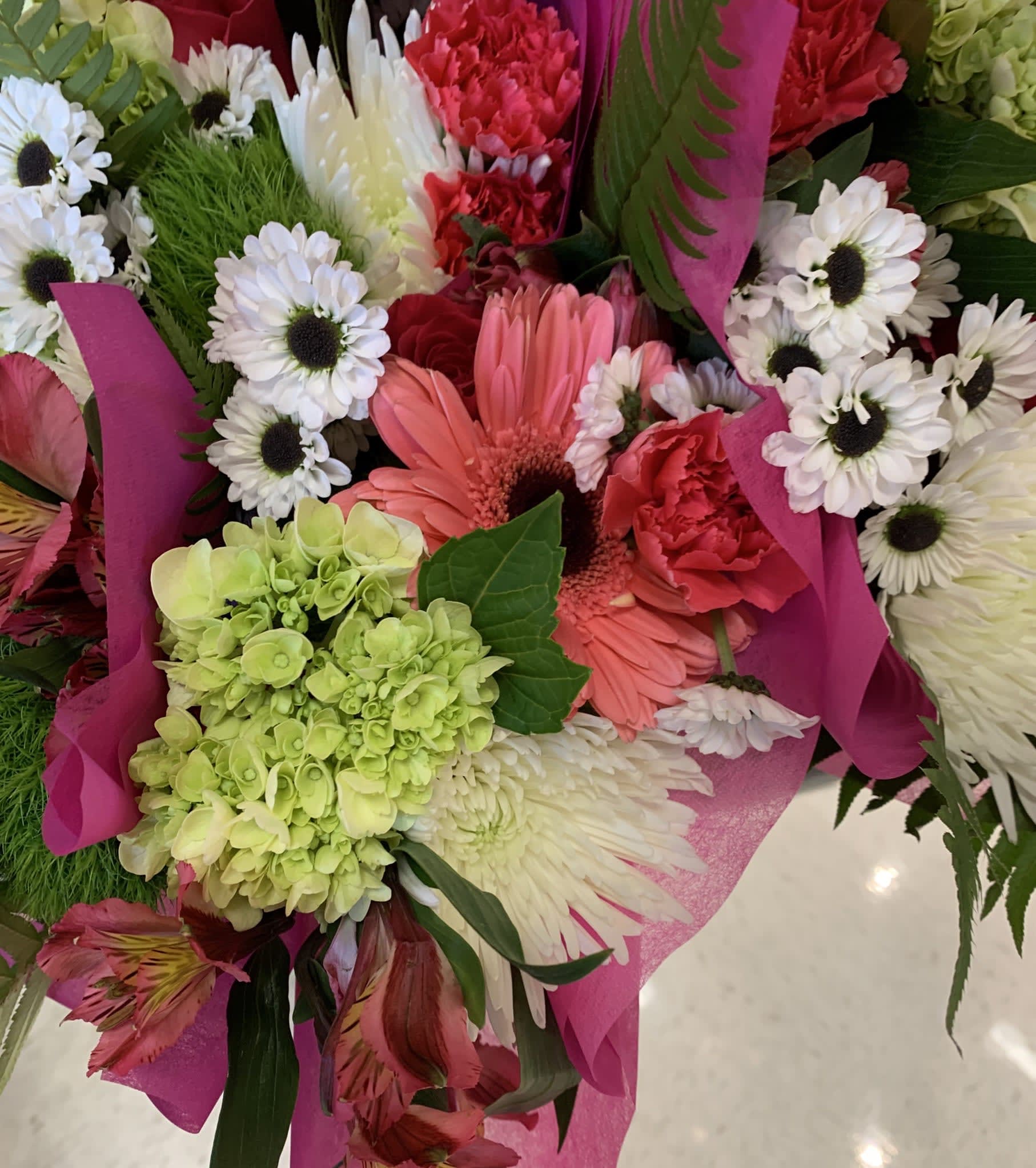 Mixed bouquet with pink gerbera daisies, white daisies, and green hydrangea