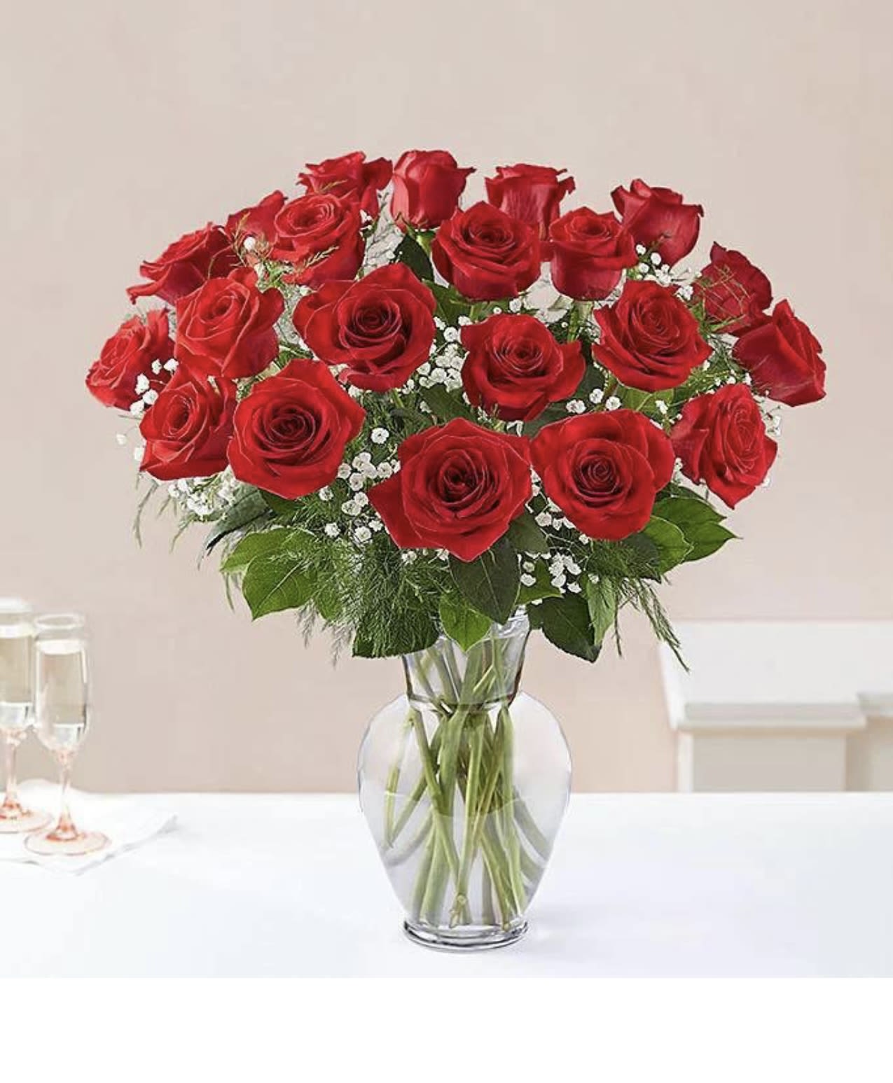 Red roses arranged in a clear glass vase with white filler flowers