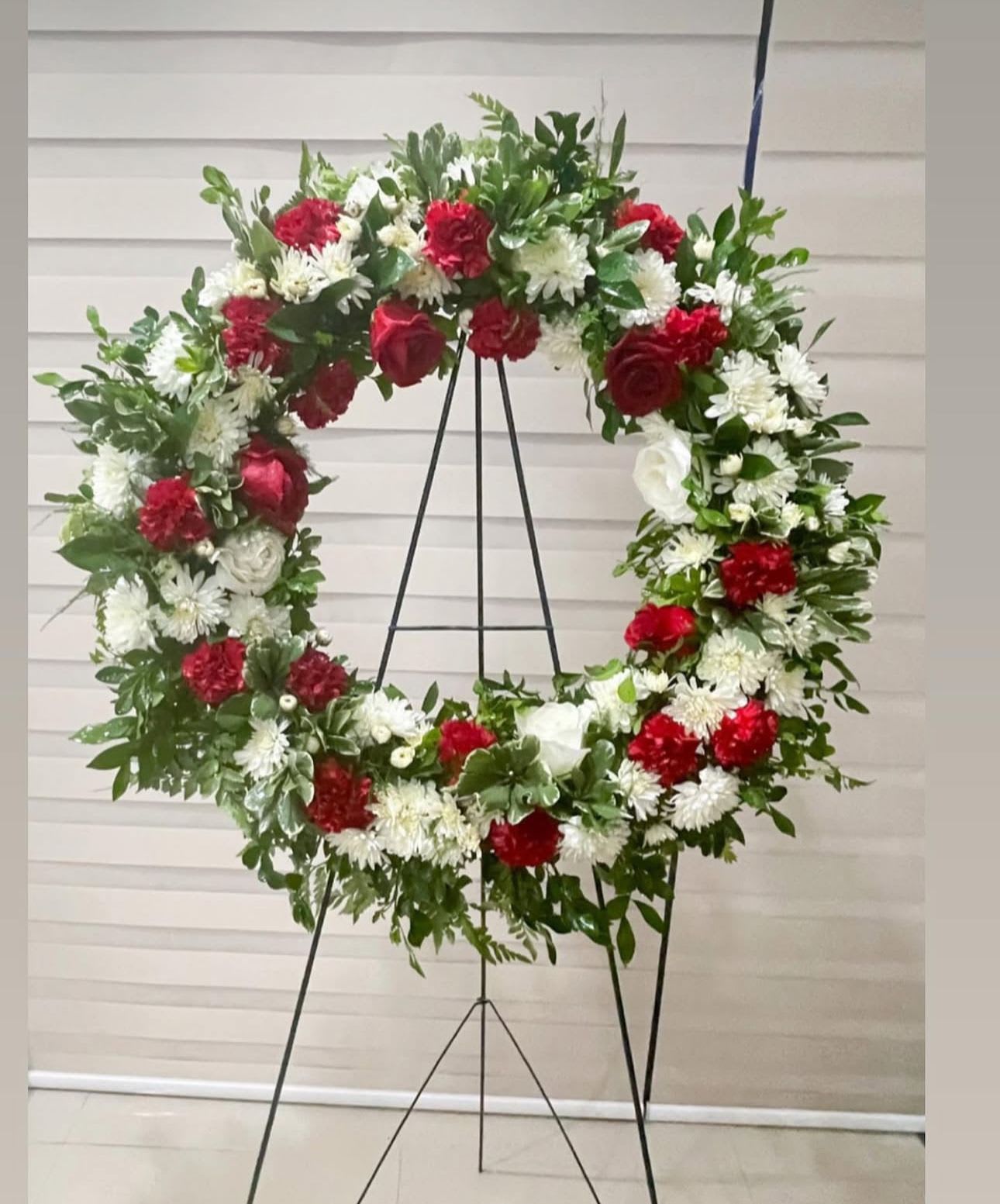 Large red and white floral wreath on a black stand