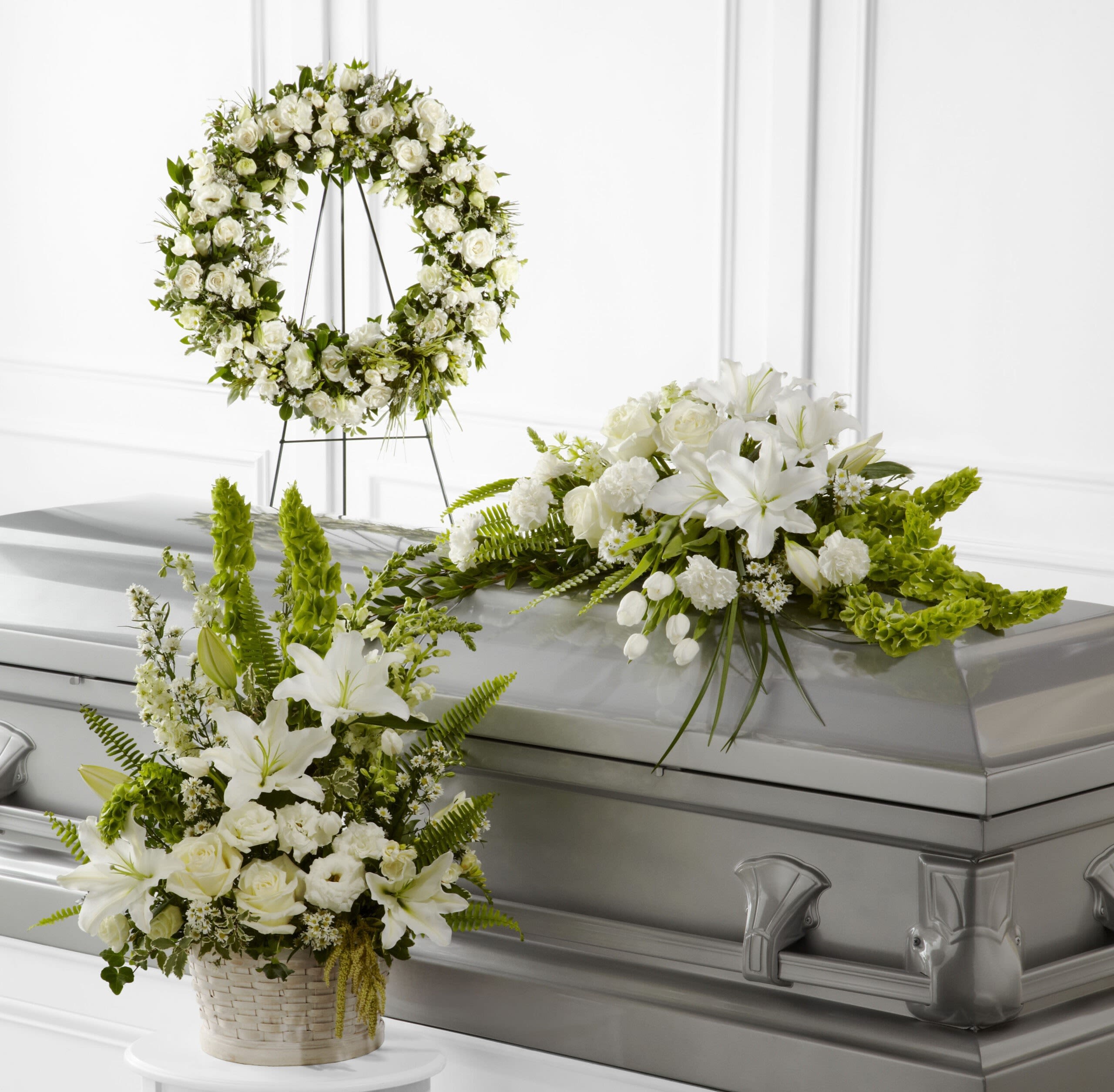 White floral funeral arrangements around a silver casket