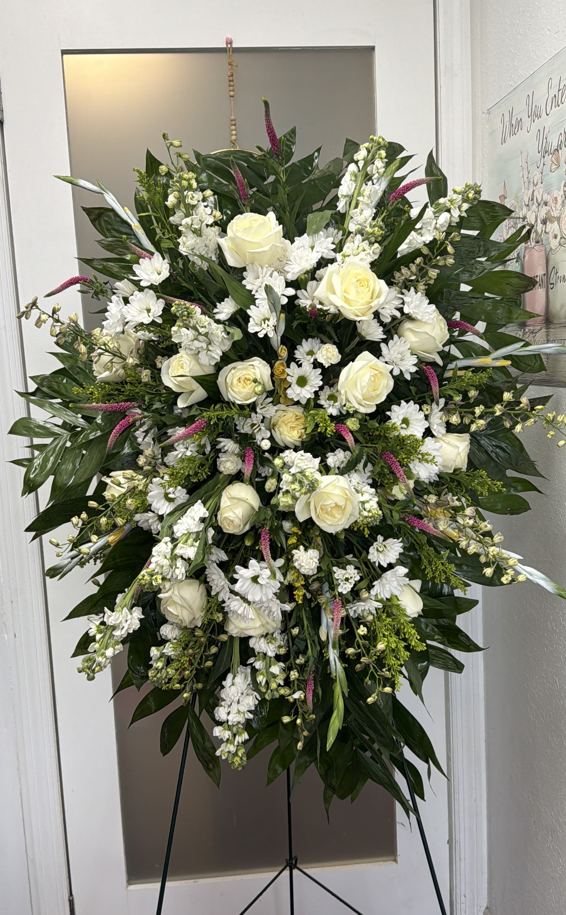 Large white floral standing spray with roses and daisies on an easel