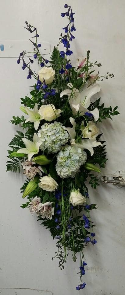 Tall floral spray with white lilies, roses, blue delphinium, and hydrangeas