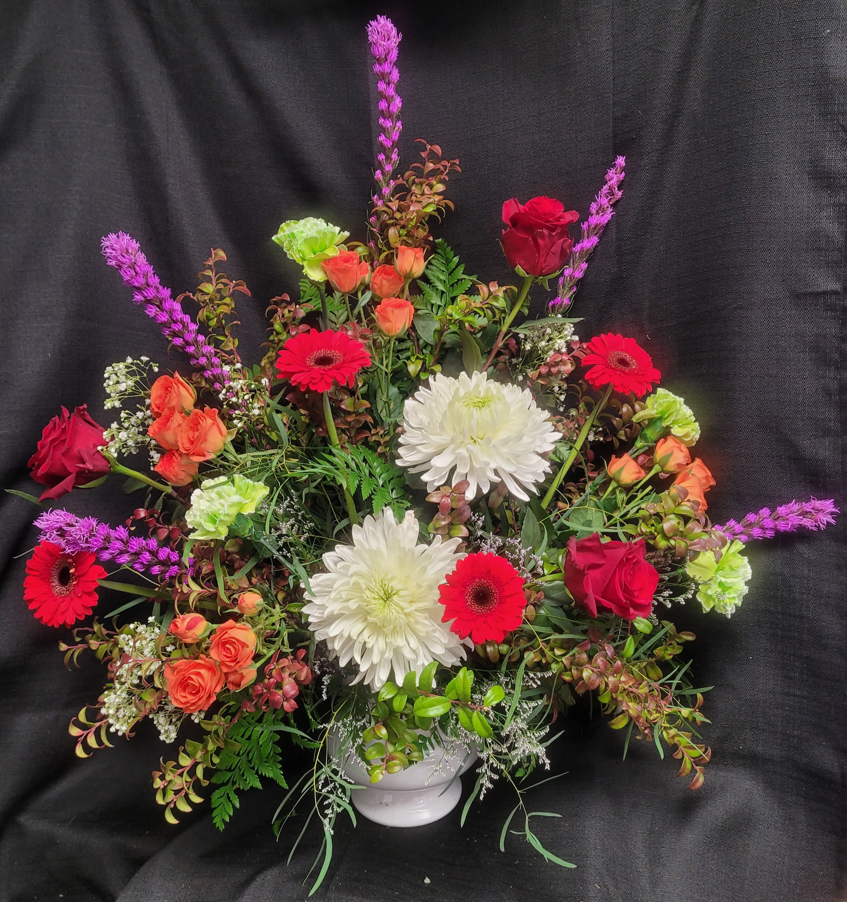 Mixed bouquet in a white vase with red, orange, and white flowers