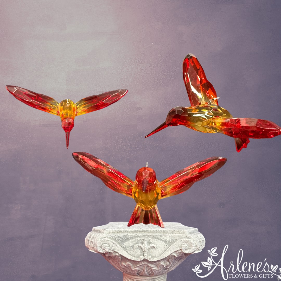 Three crystal hummingbird figurines on a decorative pedestal