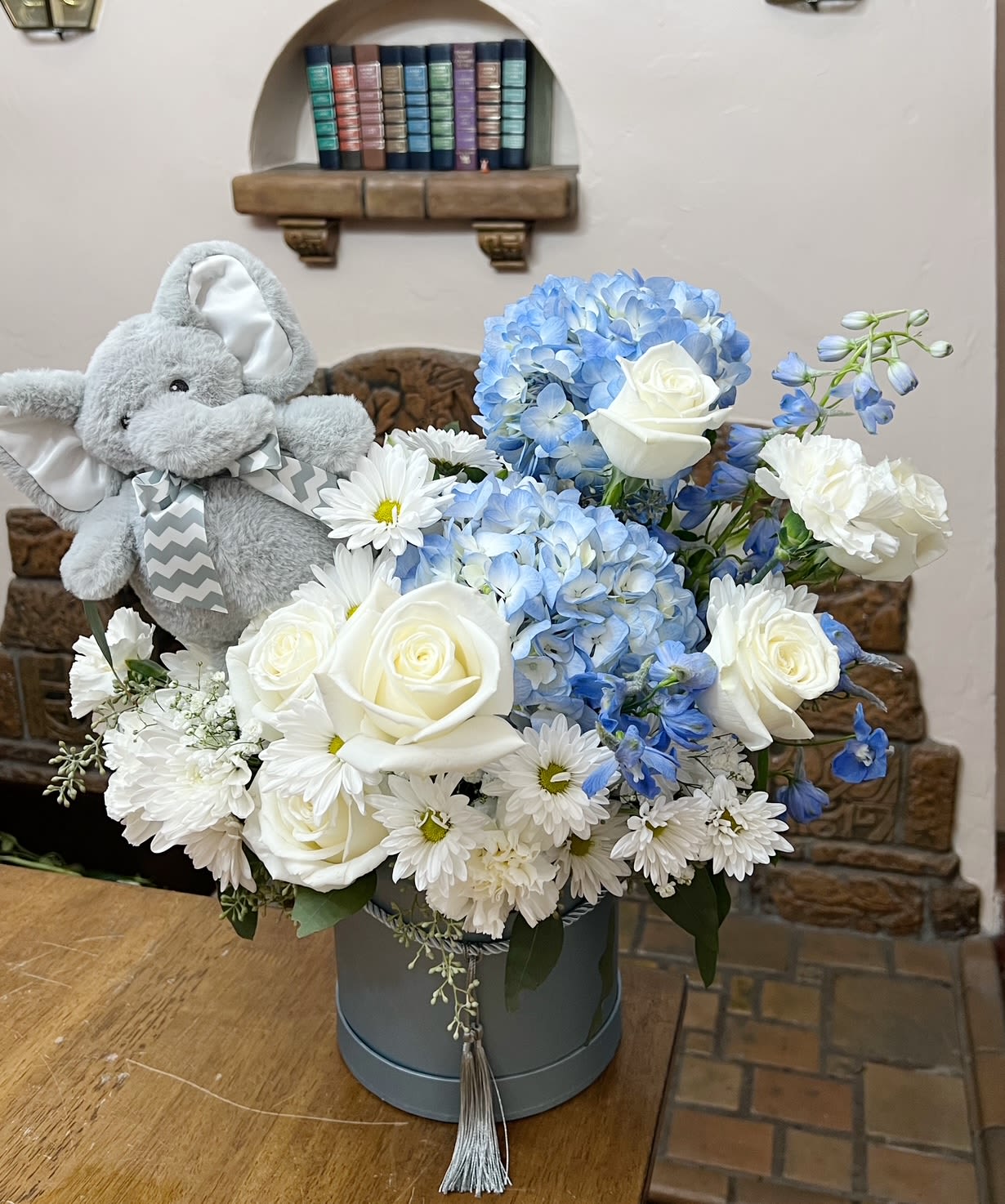 Blue and white flower arrangement with a plush elephant in a hatbox