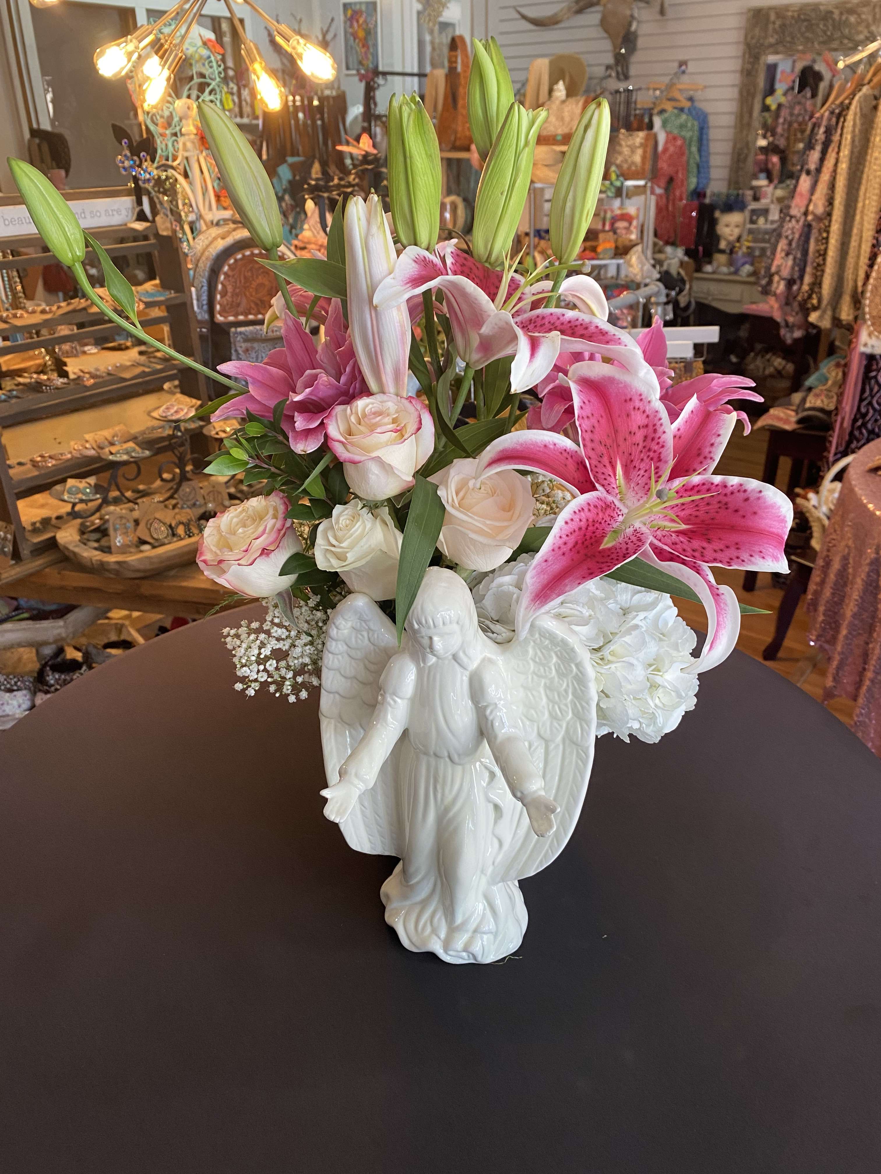 Pink lilies and white roses arranged in a white angel vase