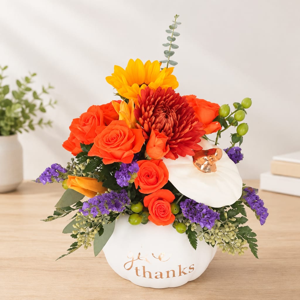 Bright mixed flower arrangement in a white pumpkin-shaped container