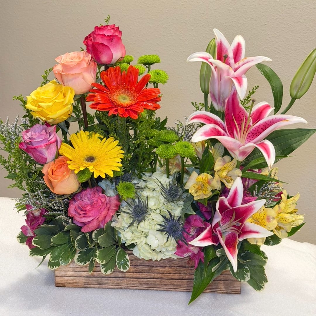 Mixed bouquet with roses, gerbera daisies, lilies, and hydrangea in a wooden box