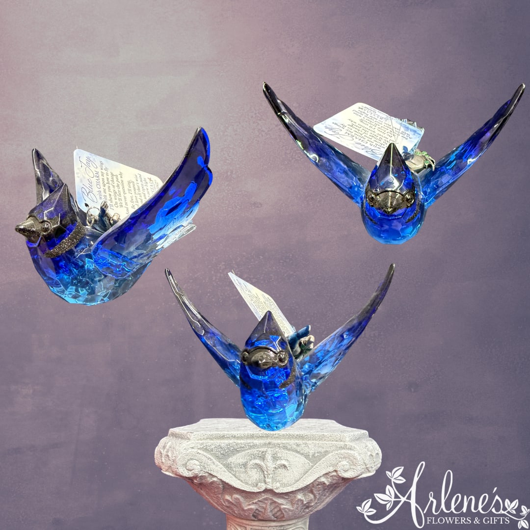 Three blue glass bird figurines displayed on a pedestal
