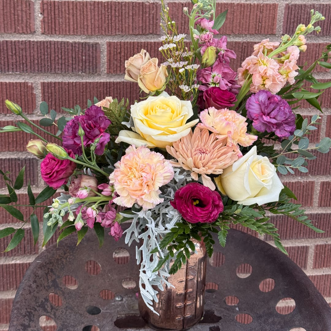 Mixed bouquet of roses, carnations, and chrysanthemums in a metallic vase