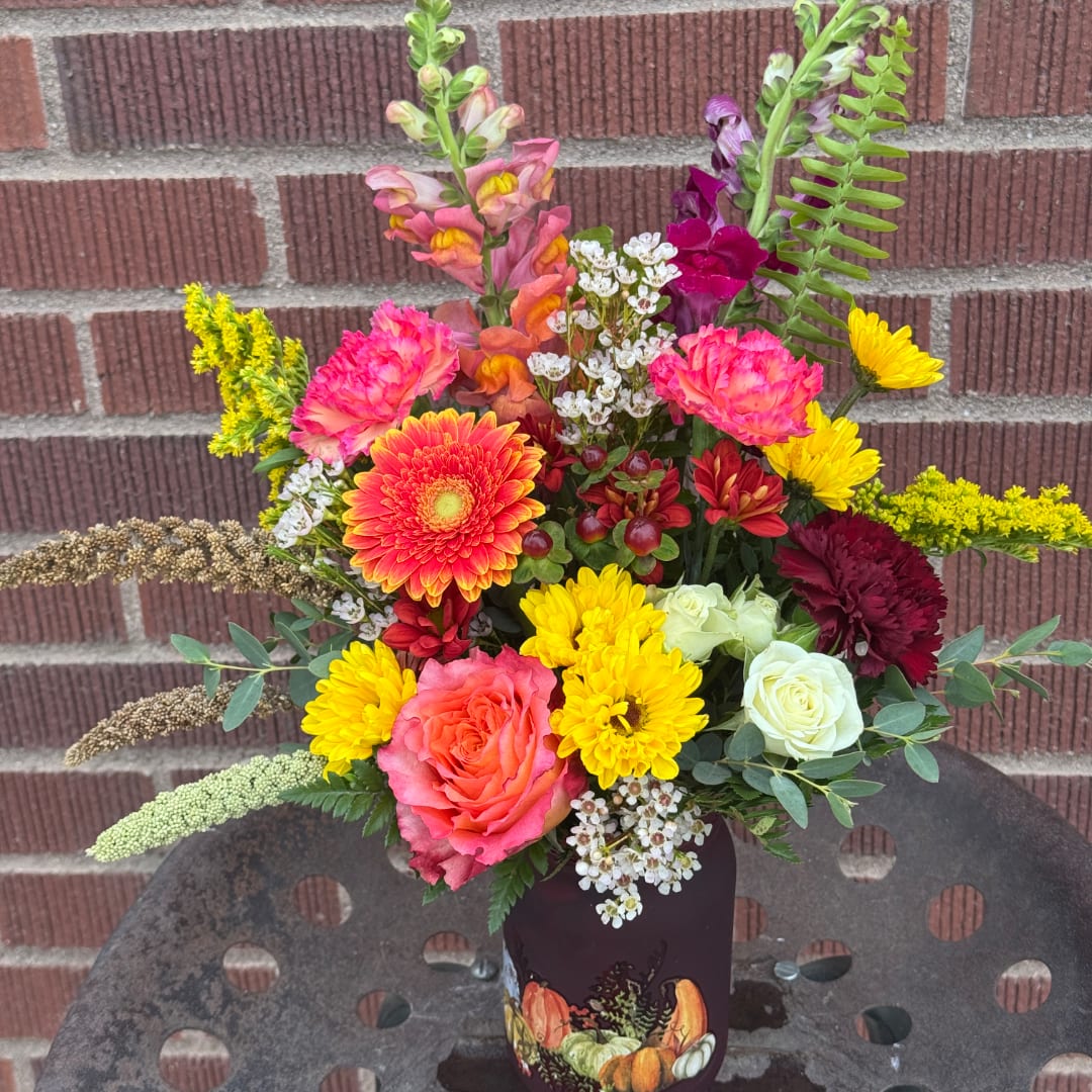 Colorful mixed bouquet in a decorated vase against a brick wall