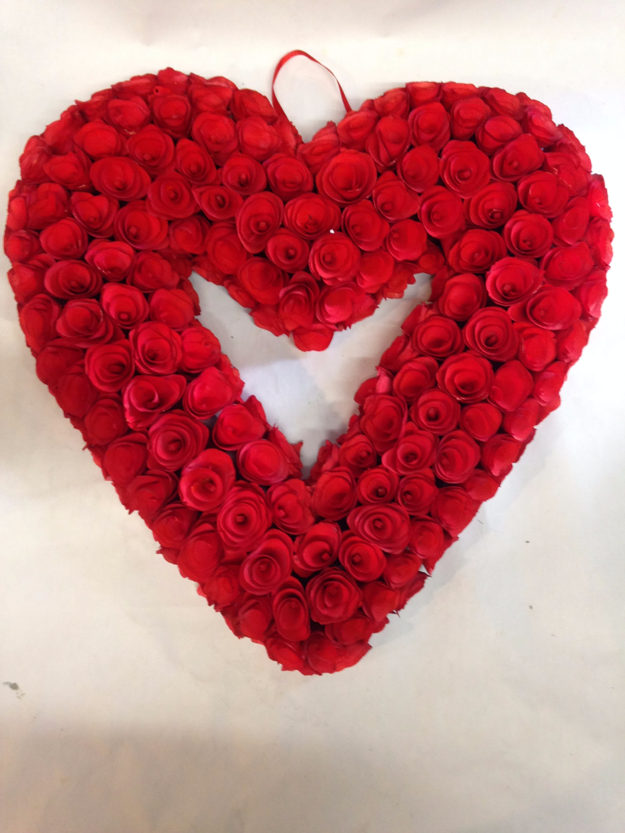 Heart-shaped arrangement of red roses on a white background