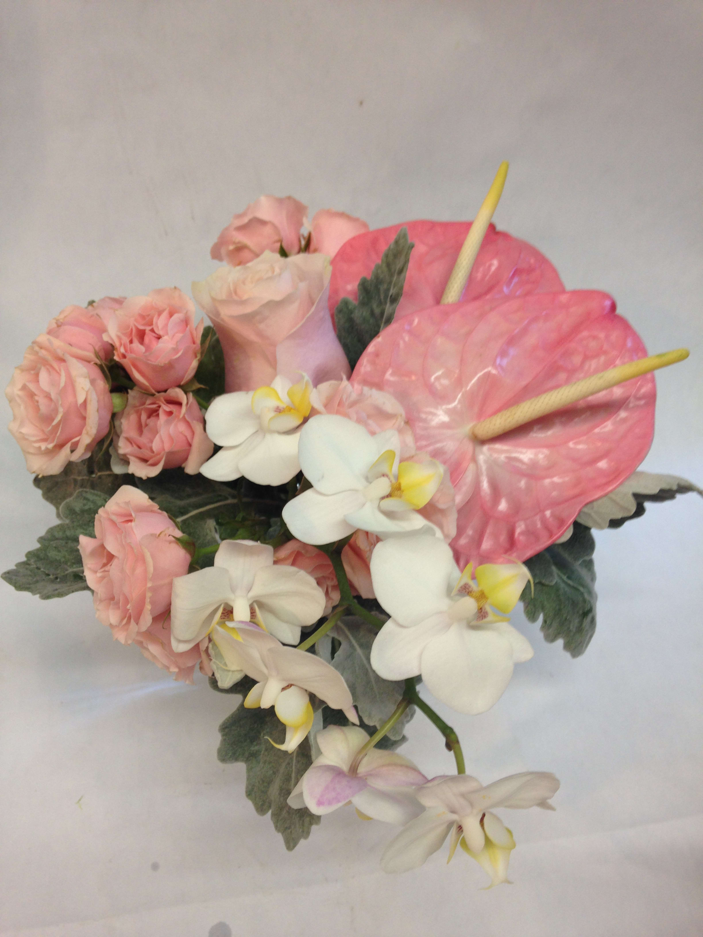 Pink roses and white orchids arranged with pink anthuriums