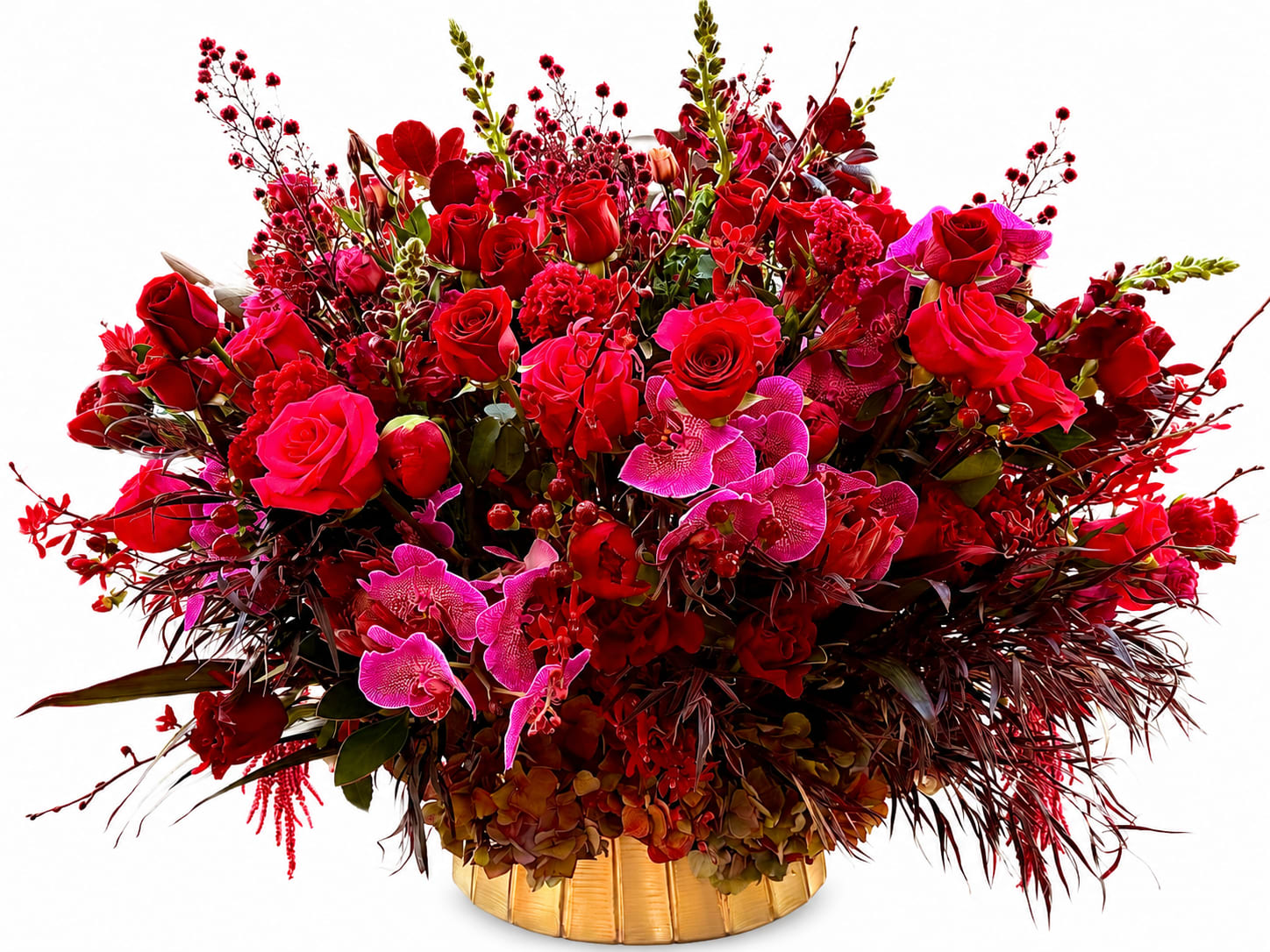 The Scarlet Garden  - Lush waves of red roses and bright pink blooms make a richly romantic statement in this large, densely packed flower arrangement - a perfect anniversary bouquet or Valentine's Day surprise that also reads celebratory enough for milestone birthdays. Magenta orchid sprays punctuate the design with sculptural contrast while darker green foliage and branching accents add depth, so the person you're thinking of will feel truly cherished the moment they see it.  This wide, abundant composition layers clustered roses, orchids,  and other mixed blooms for a textured, full-bodied look; varied petal shapes create visual movement across the arrangement. Finished in a polished gold vase, the saturated reds and magentas feel even more dramatic and formal - an elegant presentation that arrives ready to display and enjoy.