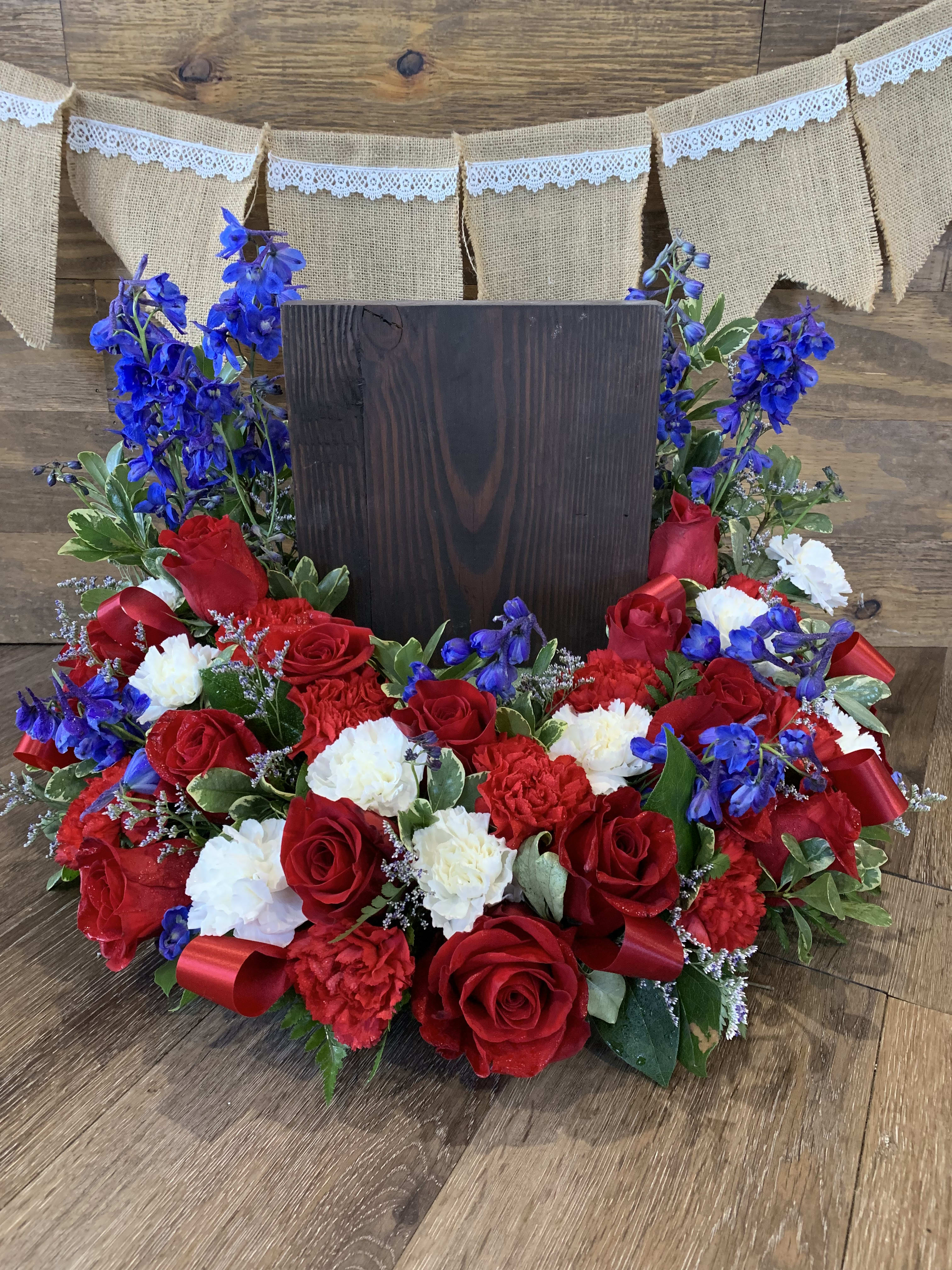 Red roses and white carnations arranged around a dark wooden sign