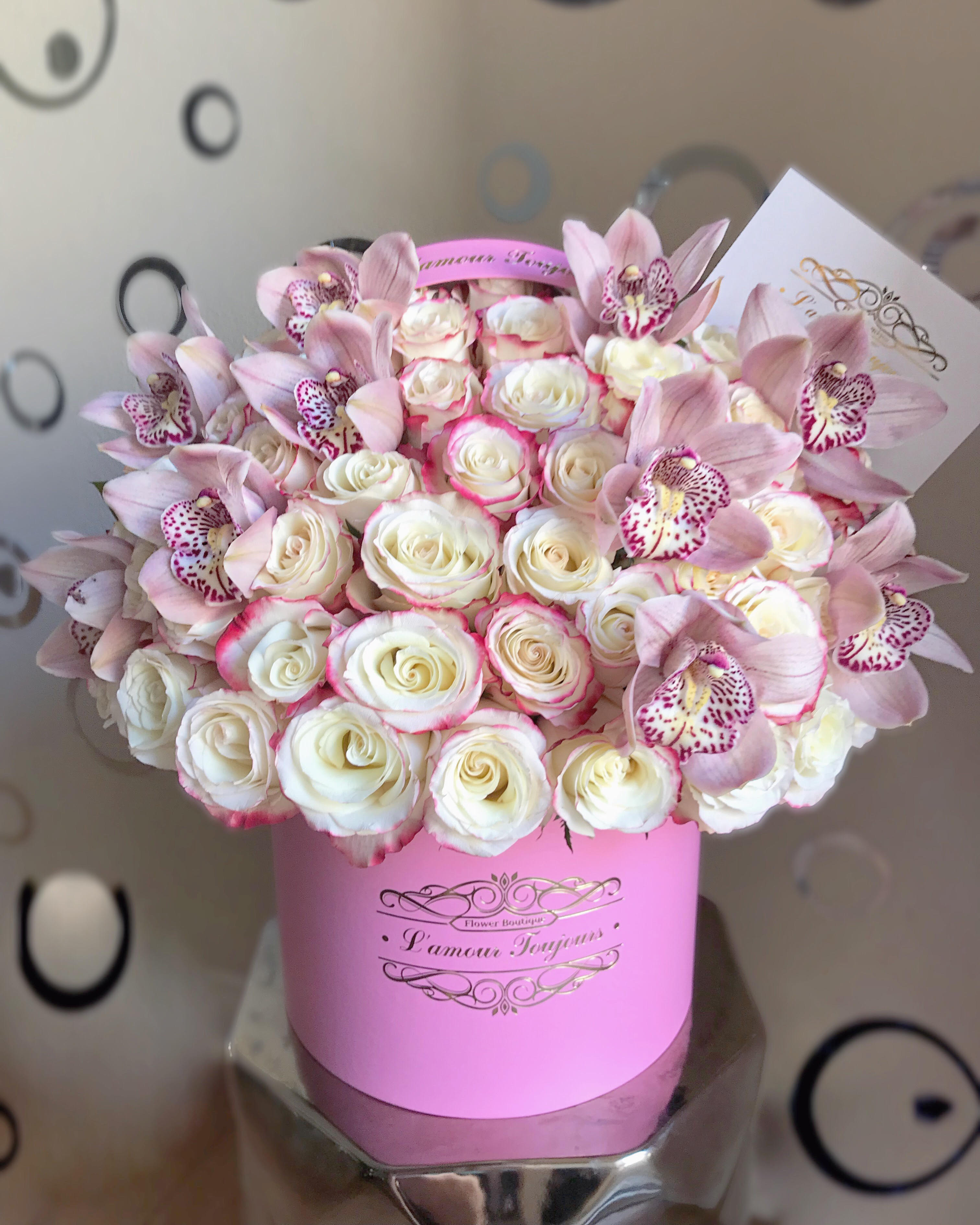 Pink and white roses with pale pink orchids in a pink box