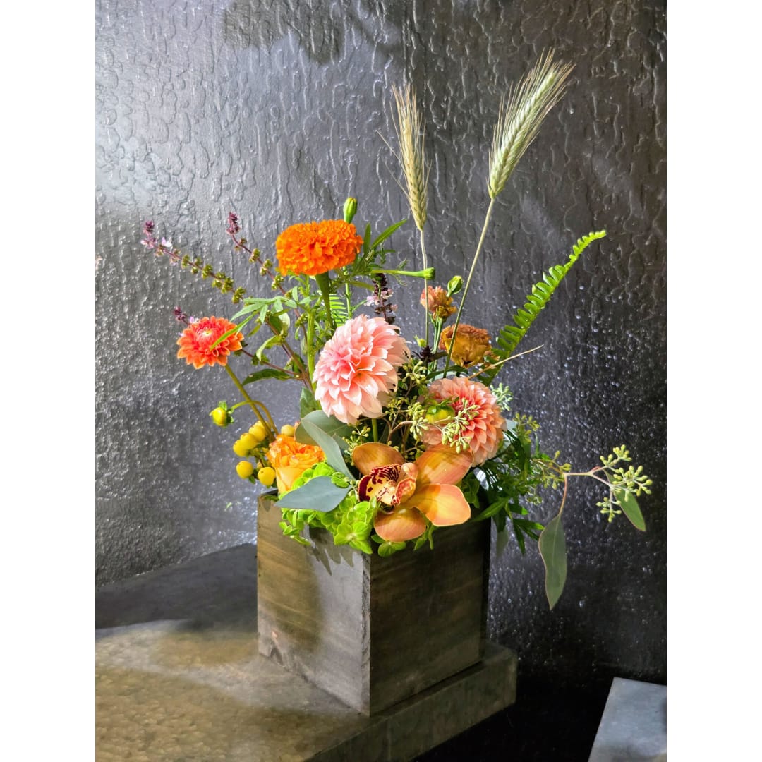Mixed floral arrangement in a square wooden box with tall grasses