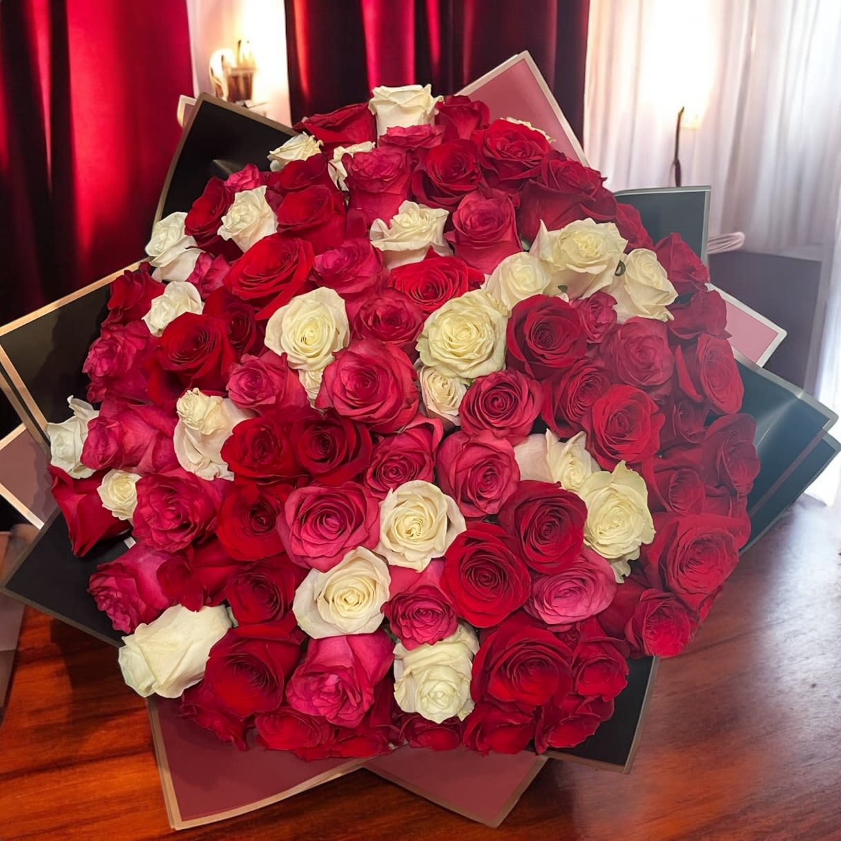 Large bouquet of red, pink, and white roses in layered wrapping