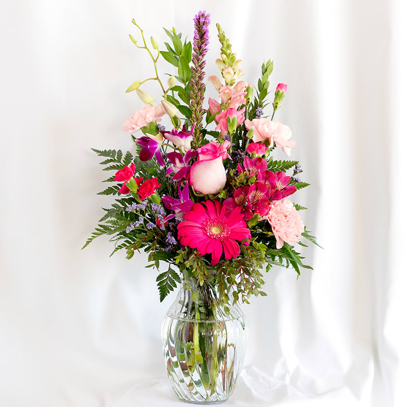 Mixed pink and purple flower arrangement in a clear glass vase