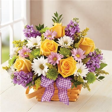 Basket arrangement of yellow roses, white daisies, and purple flowers with a ribbon