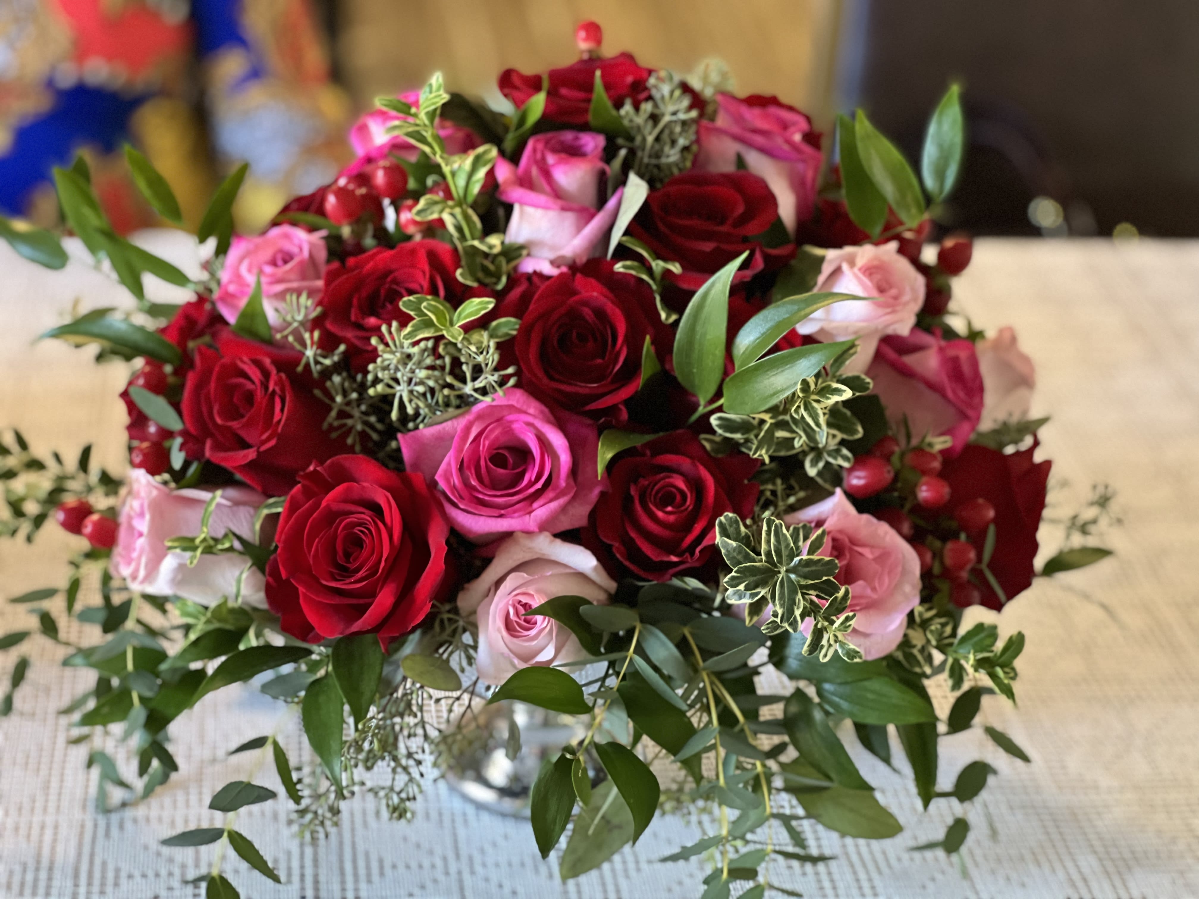 Bouquet of red and pink roses with greenery in a glass vase