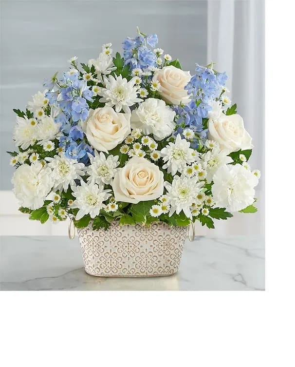 Loving Remembrance™ Blue and White - Celebrate the life of a loved one with our beautiful floral tribute. A mix of blooms in soothing shades is a symbol of enduring love. Designed in our Remembrance Cachepot, featuring an embossed pattern and finished with a gold brushed ivory surface.