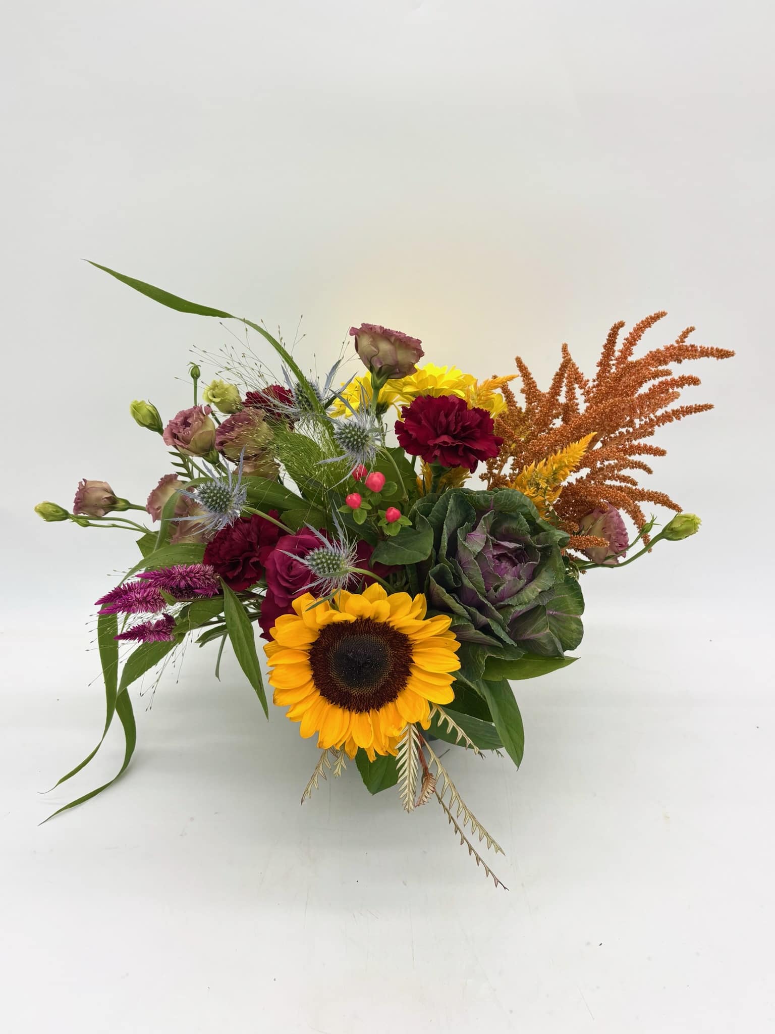 Mixed bouquet with a sunflower, burgundy blooms, and orange accents