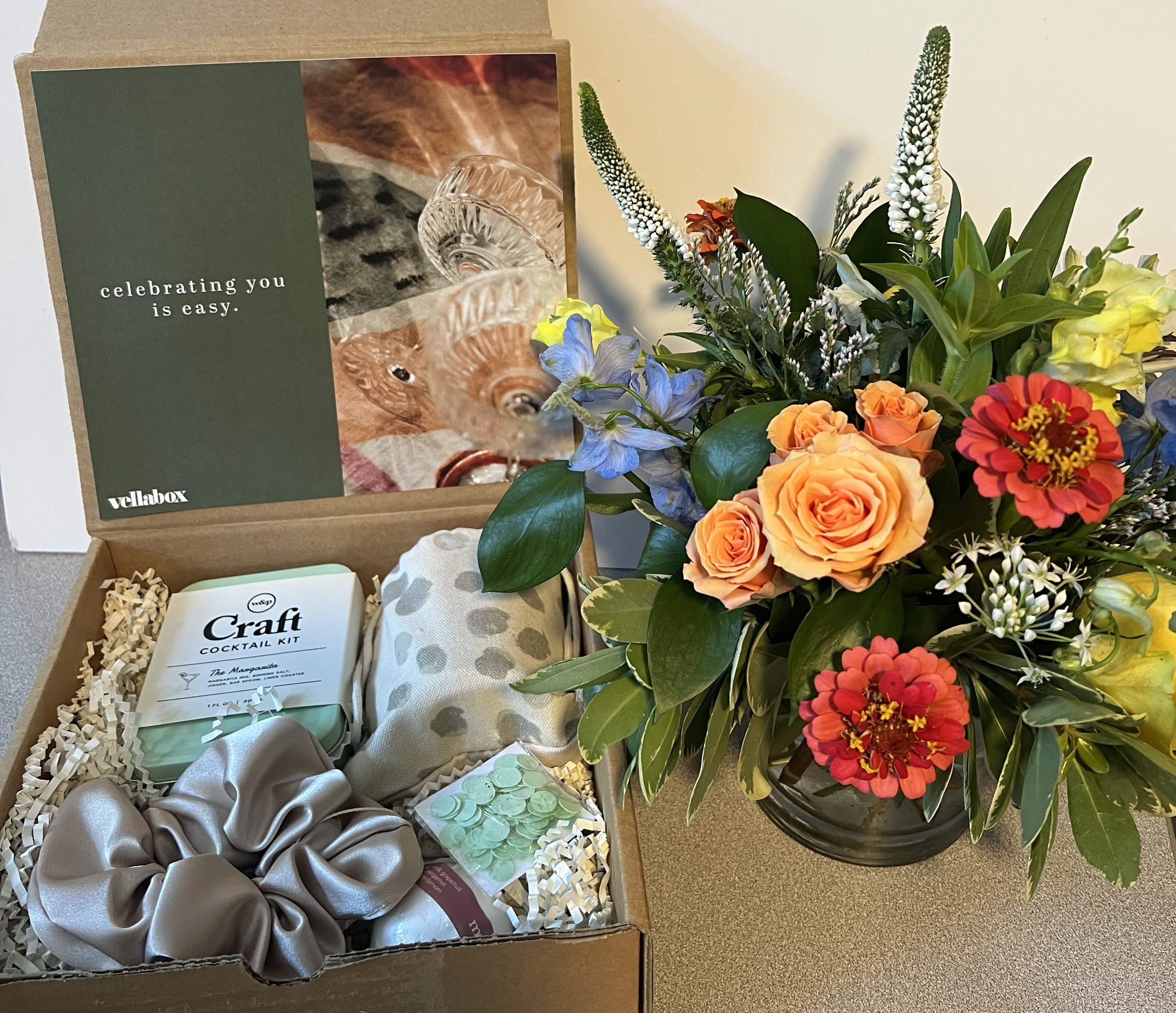 Gift box with flowers, a cocktail kit, and accessories beside a colorful bouquet