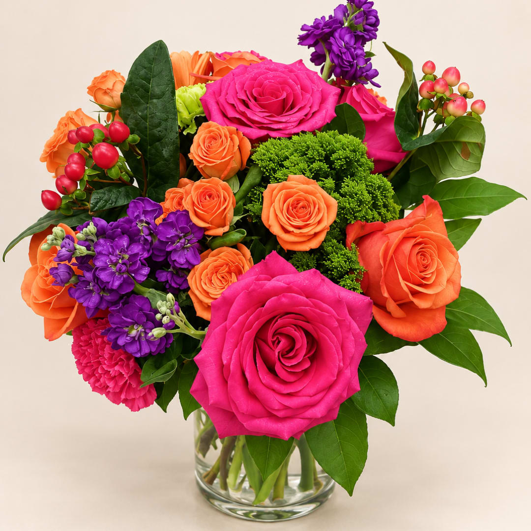 Bright mixed bouquet of pink, orange, and purple flowers in a clear glass vase
