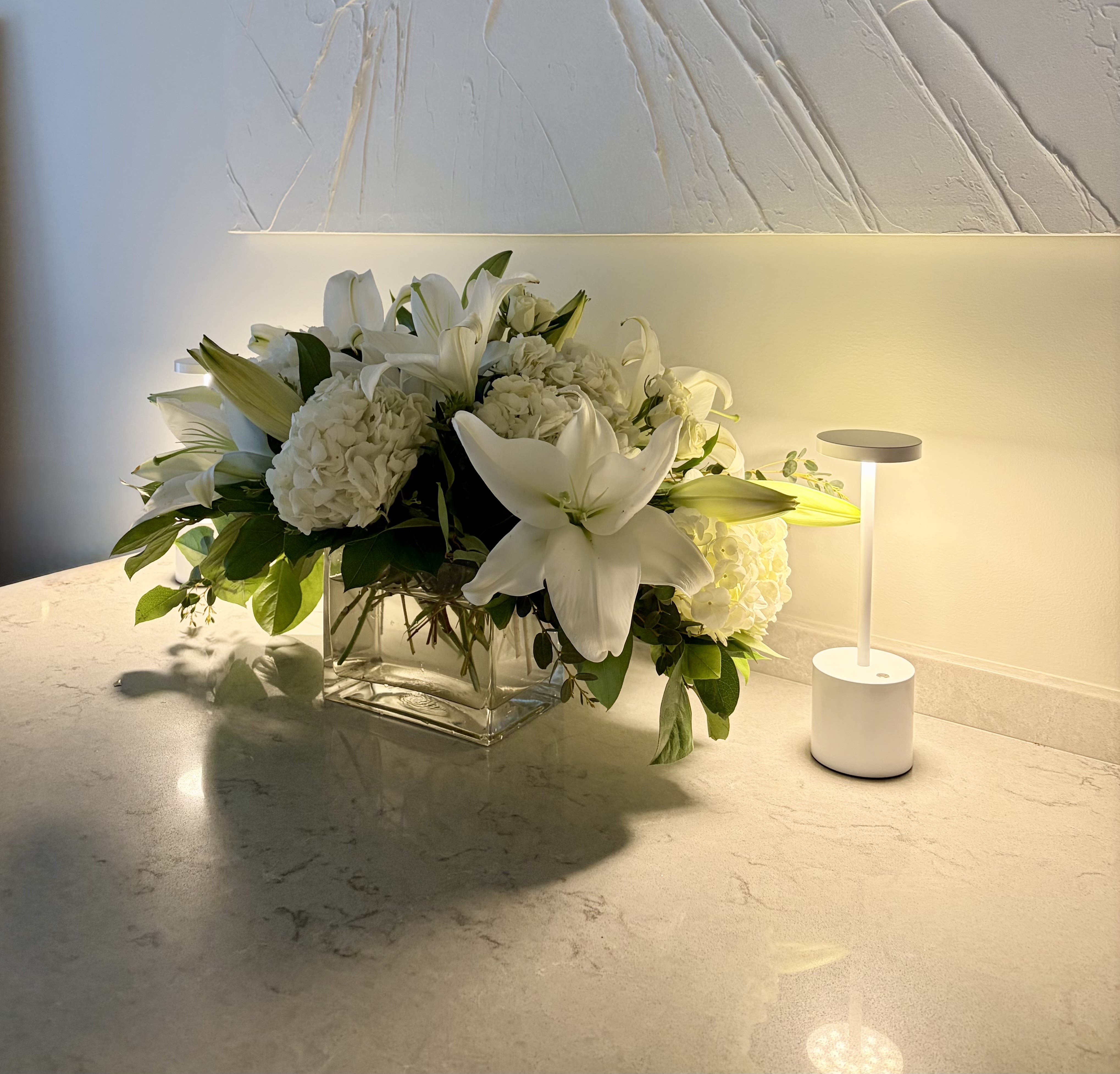 White lilies and hydrangeas in a clear glass vase