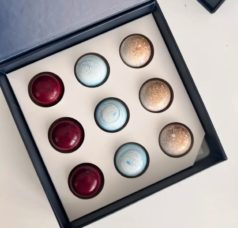 Box of assorted round chocolates in red, blue, and gold