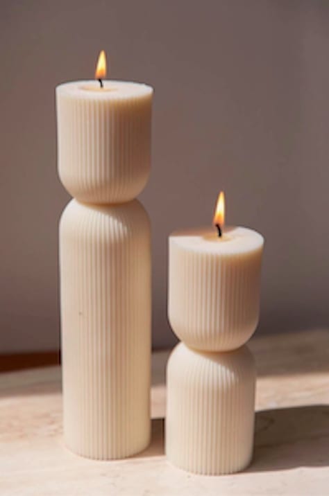 Two lit cream pillar candles with ribbed sides
