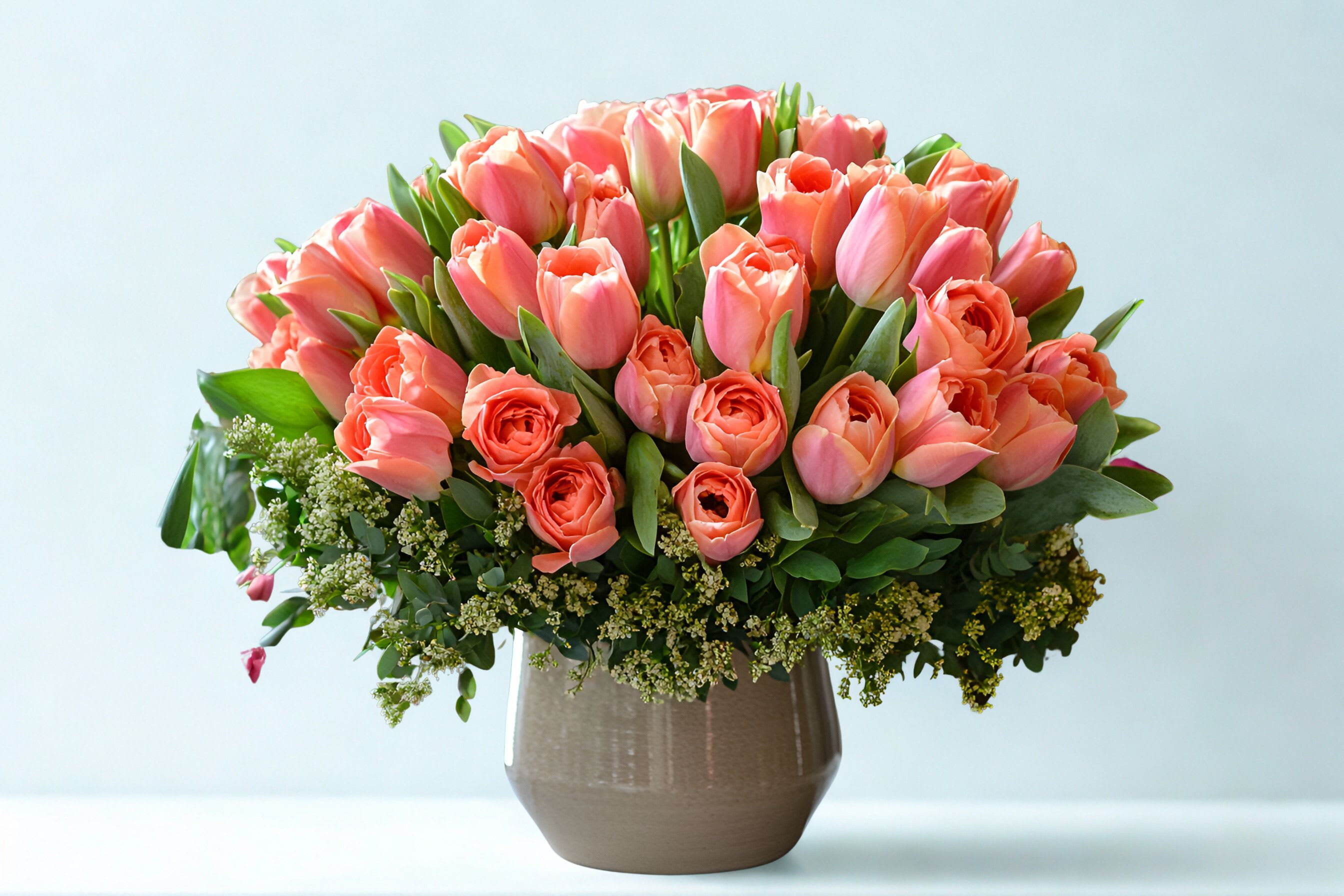 Pink tulips and coral roses in a ceramic vase