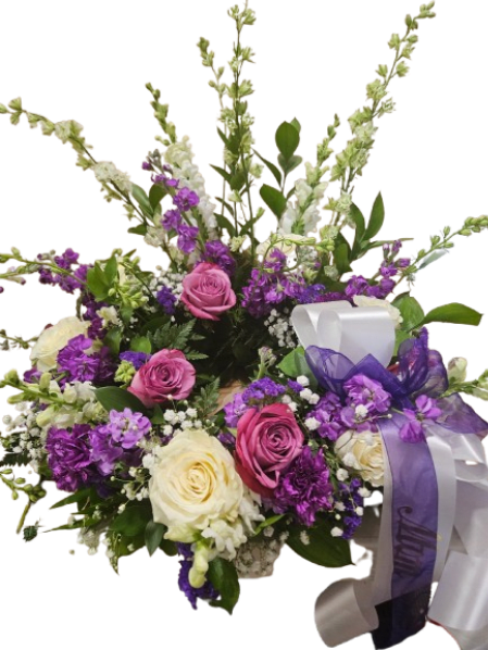 Lavender Remembrance Urn Wreath - A graceful expression of love and remembrance, the Lavender Remembrance Urn Wreath is thoughtfully designed to surround an urn with beauty, peace, and comfort. Featuring a soft blend of lavender, purple, and white blooms, this elegant tribute symbolizes serenity, dignity, and everlasting love.  Delicate roses, seasonal blossoms, and lush greenery are carefully arranged to create a gentle, garden-inspired wreath that honors a life beautifully lived. Its calming color palette offers a sense of tranquility while providing a meaningful focal point during services or memorial gatherings.  Perfect for funeral services, memorials, or celebration of life ceremonies, this urn wreath is a heartfelt way to express sympathy and support.  Specialty Ribbon $10.00 additional 