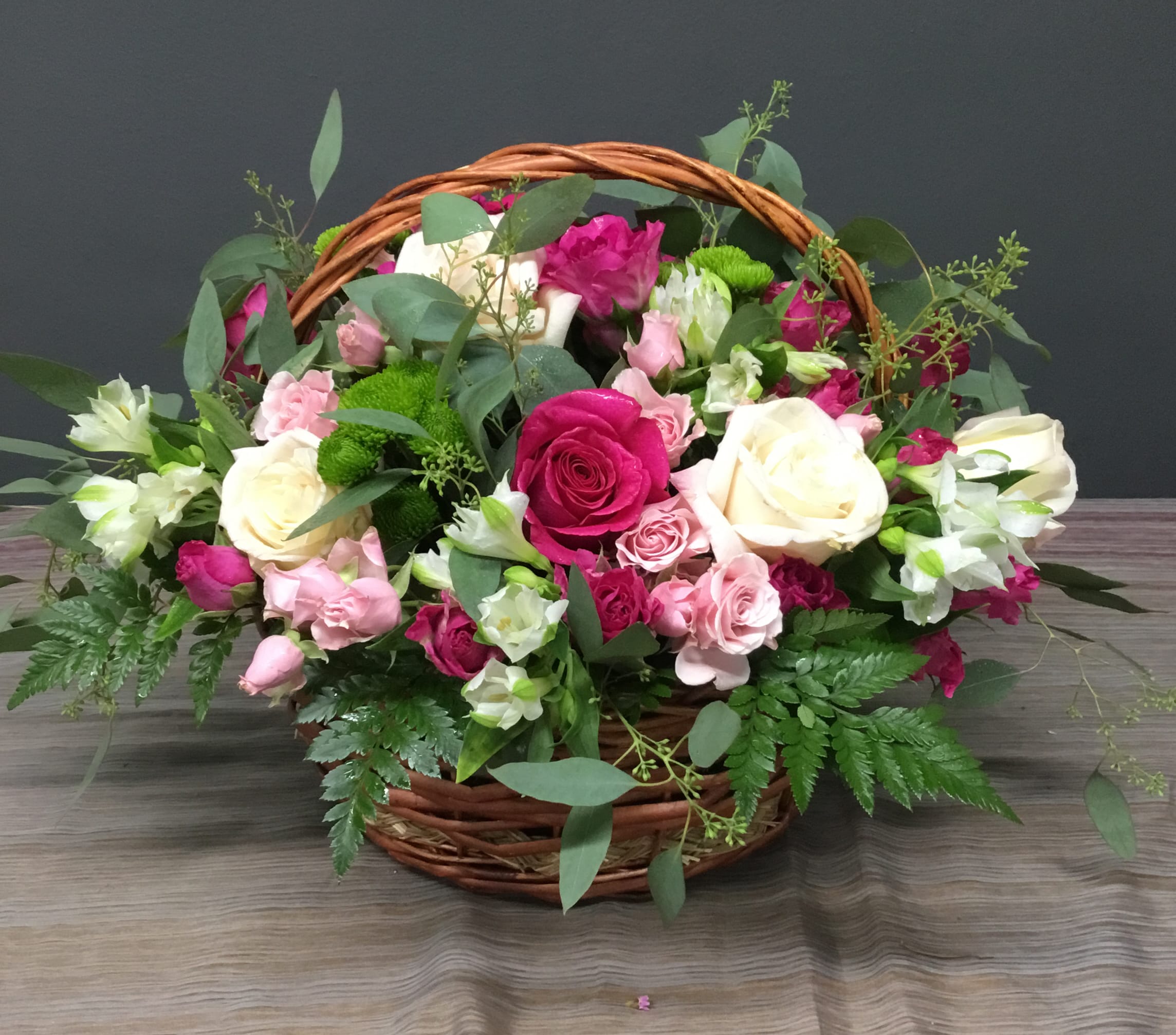 Basket of pink and white roses with greenery